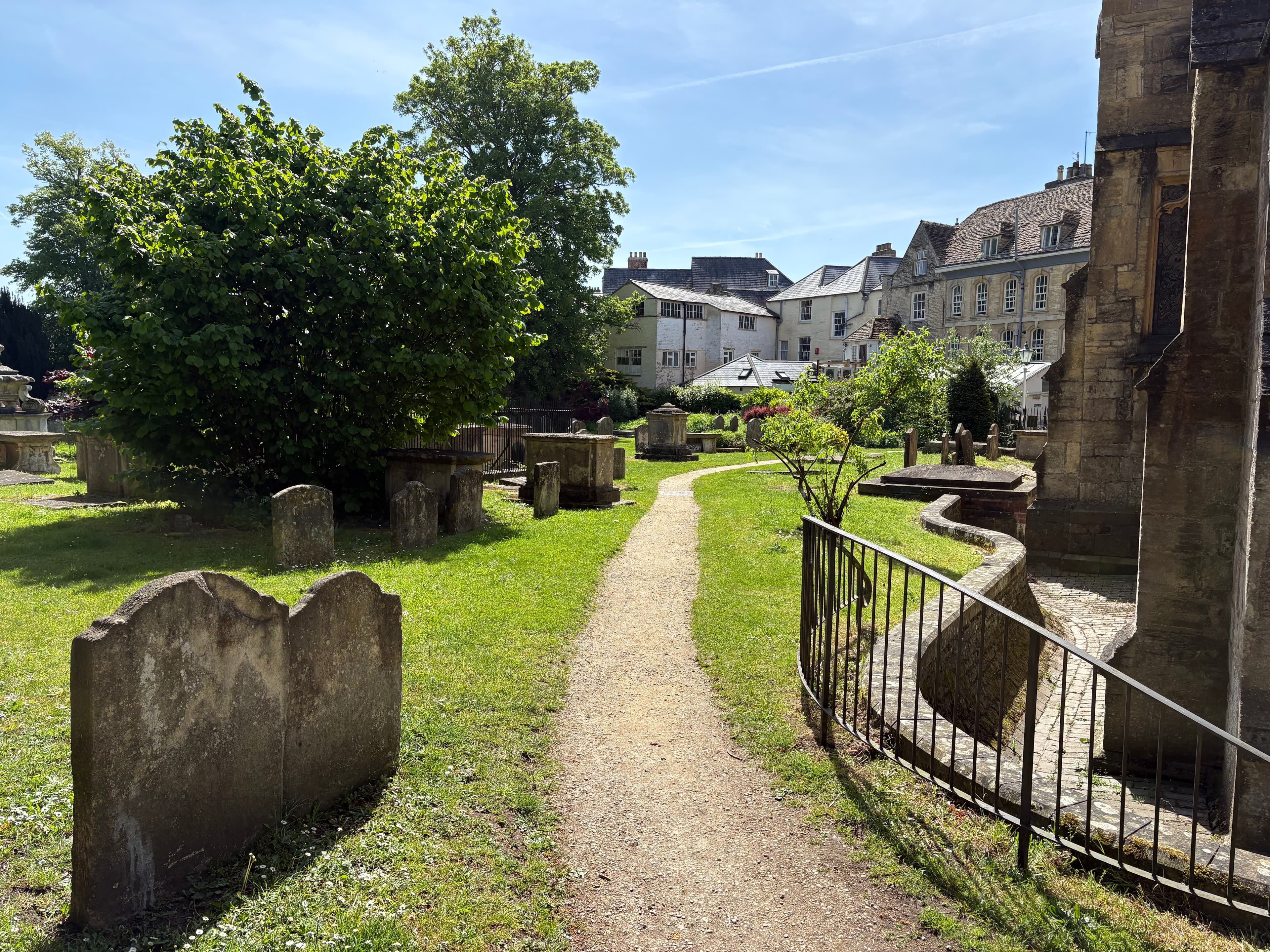 Path through the churchyard at St John the Baptist, with gravestones and townhouses beyond