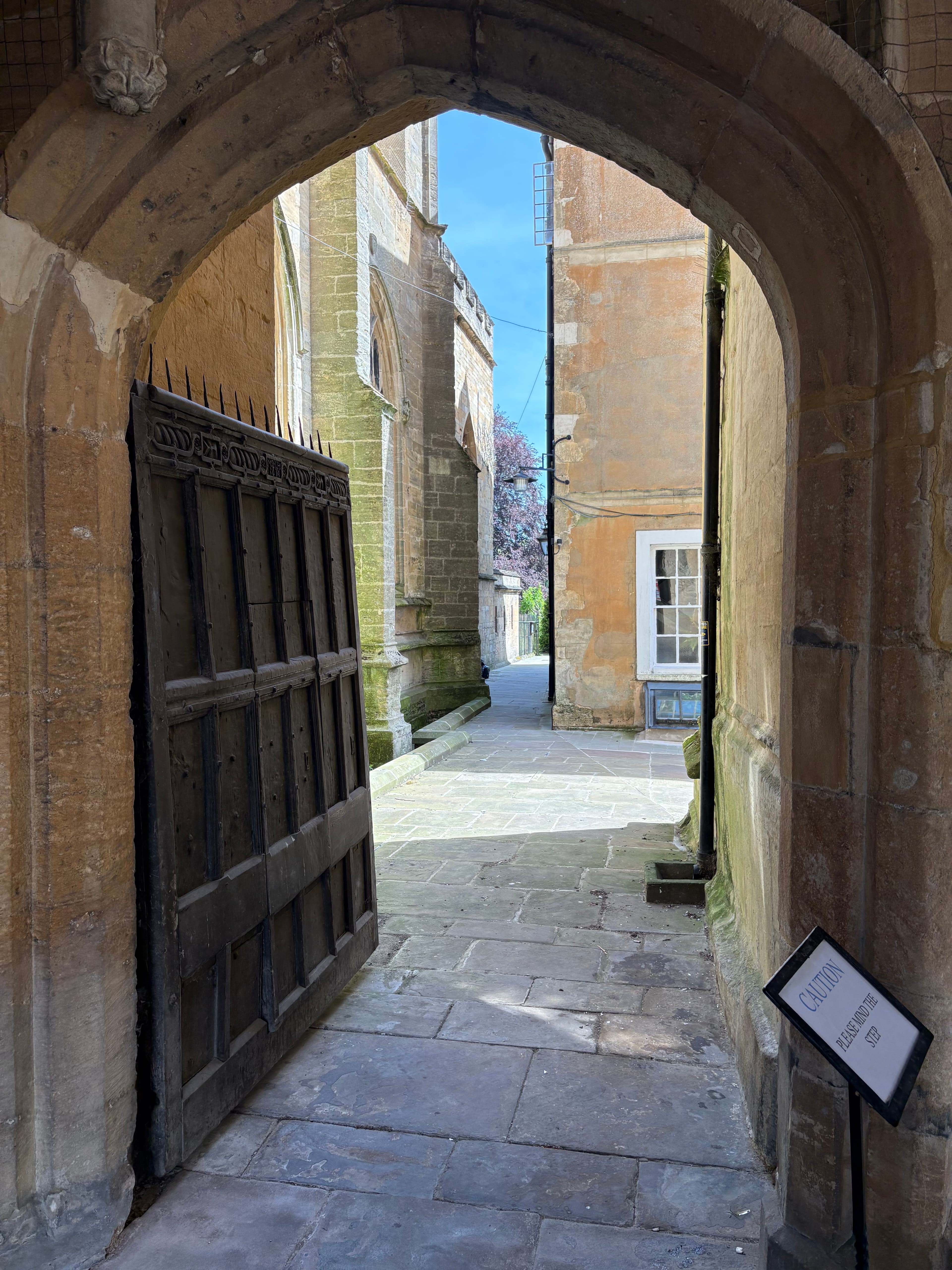 View out through the south porch's wooden gate, with stone vaulting overhead