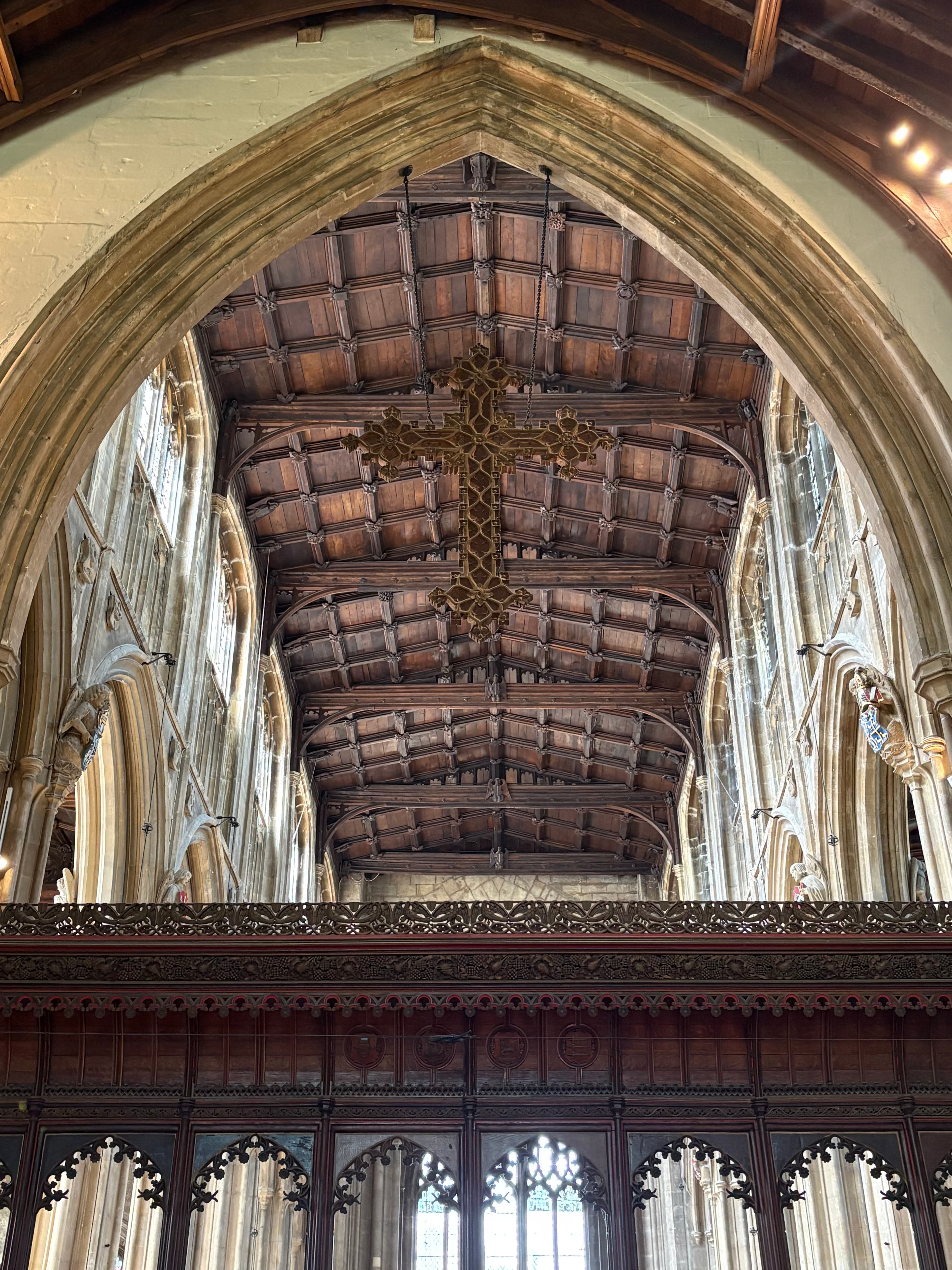 Looking up into the tower from inside the church, with an ornate cross suspended below