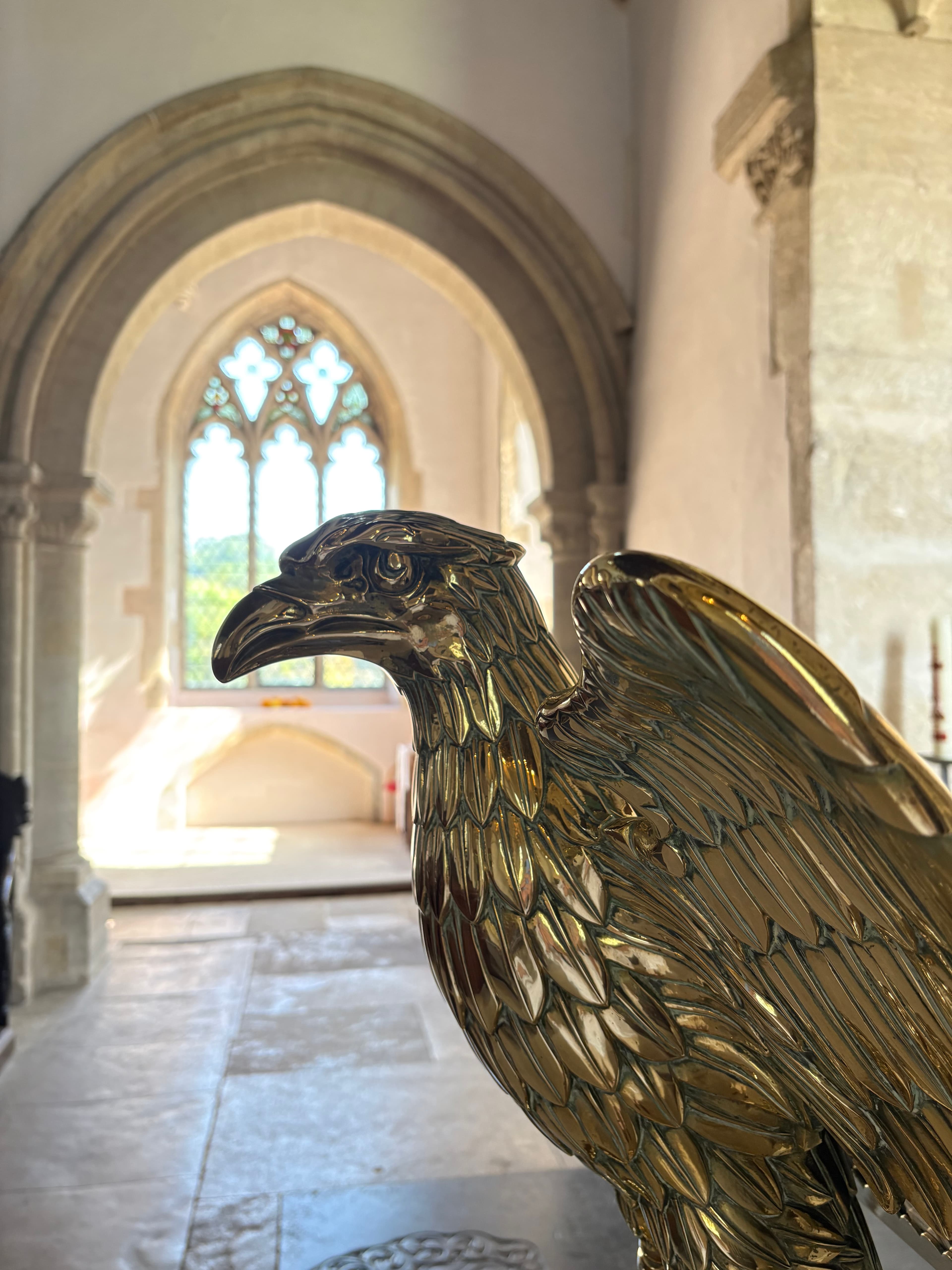 The brass eagle lectern in St Mary's, with a Gothic window beyond