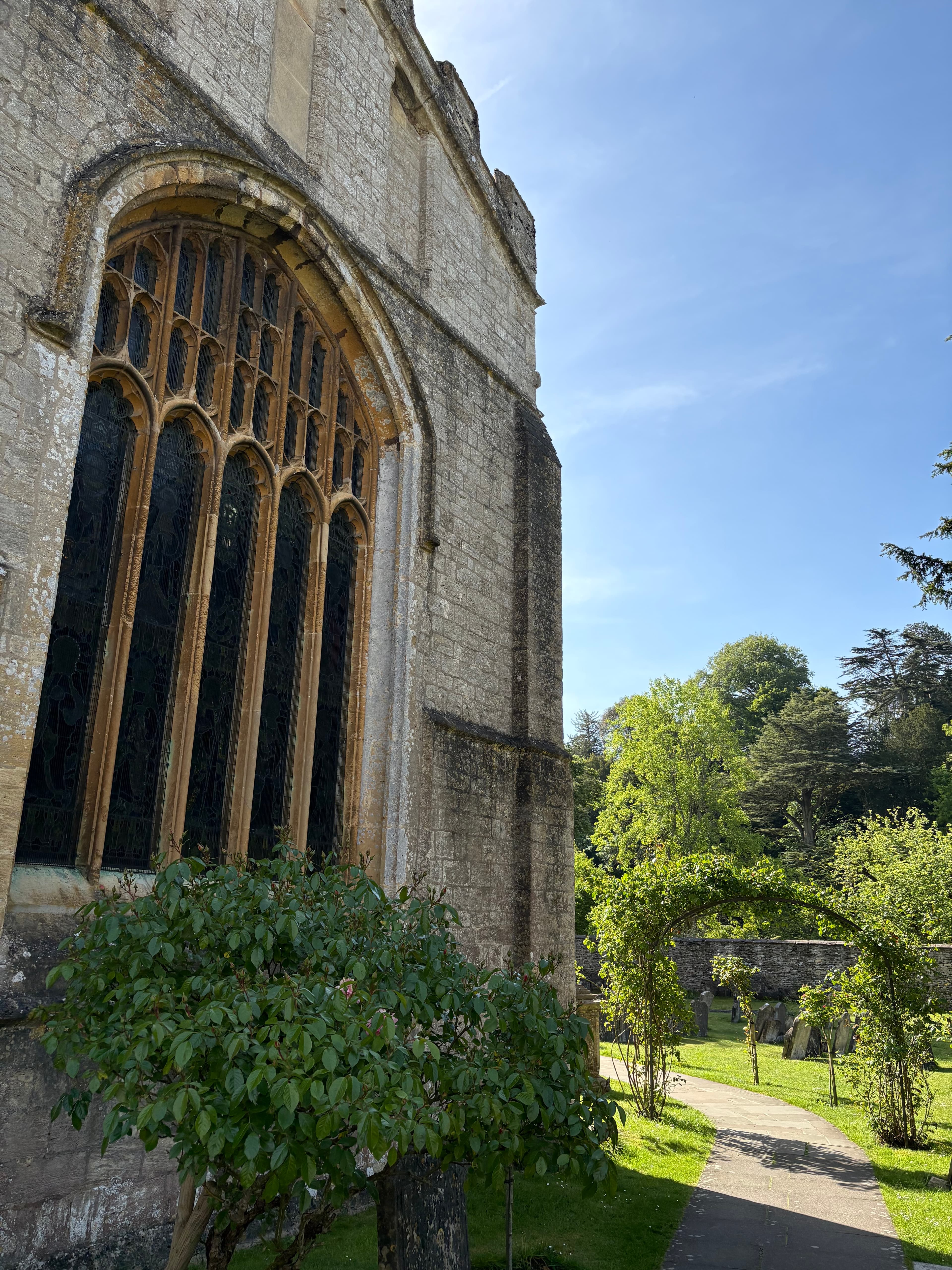 The east window of St Mary's, Bibury — Gothic tracery seen from the churchyard