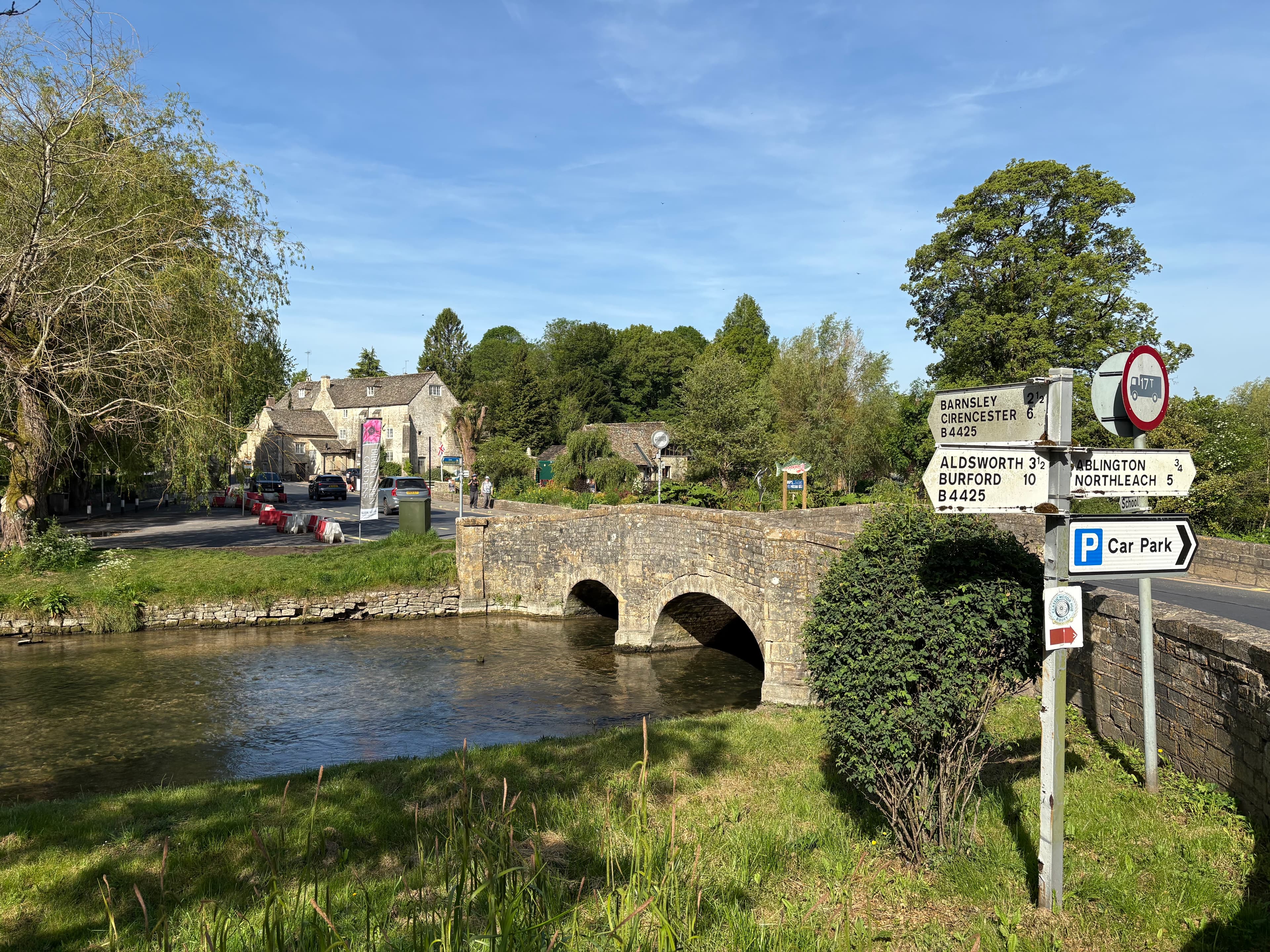 The medieval stone bridge over the River Coln, with road signs on the approach