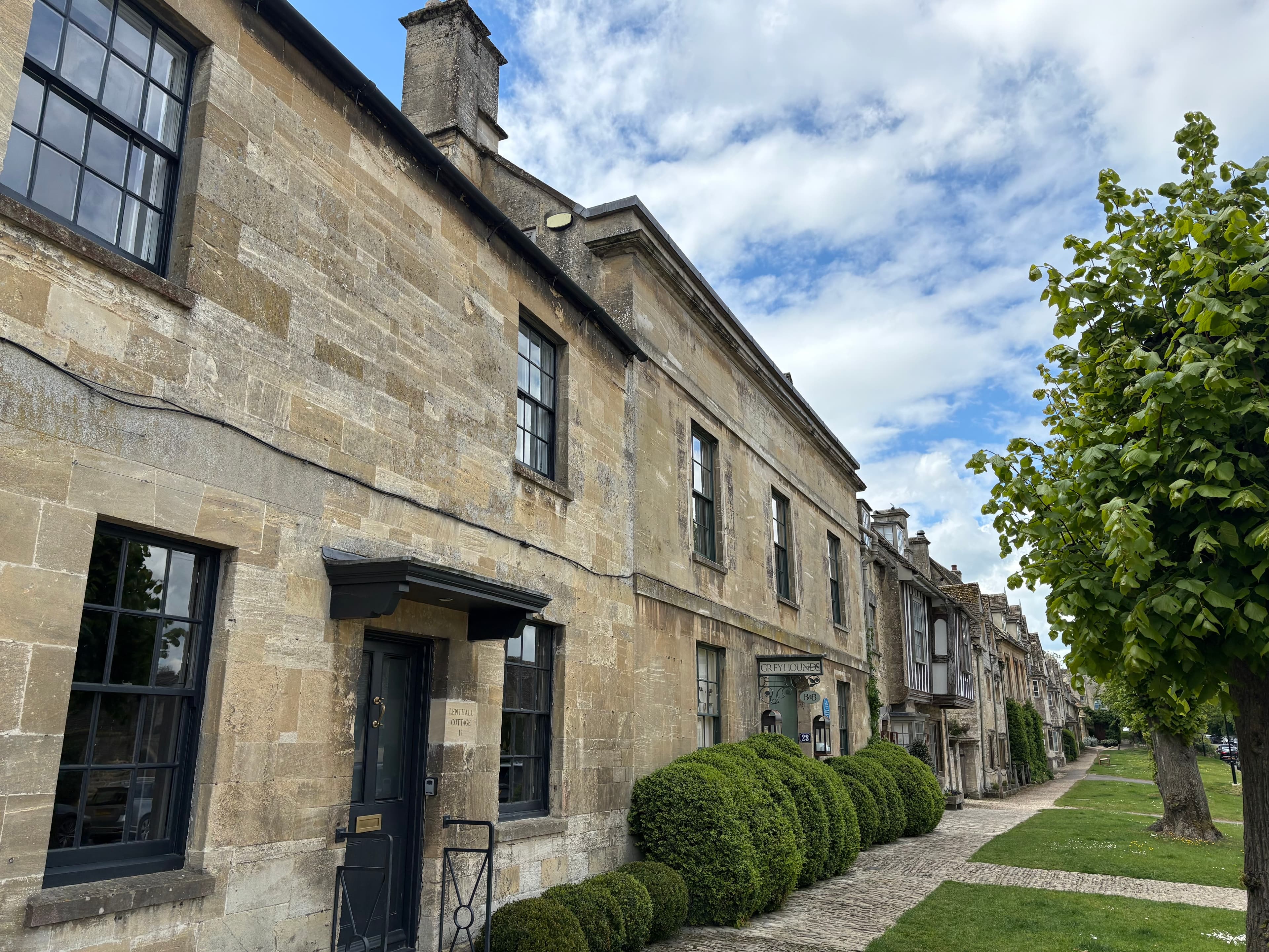 More cottages stepping down the high street — typical Cotswold limestone with clipped box hedges