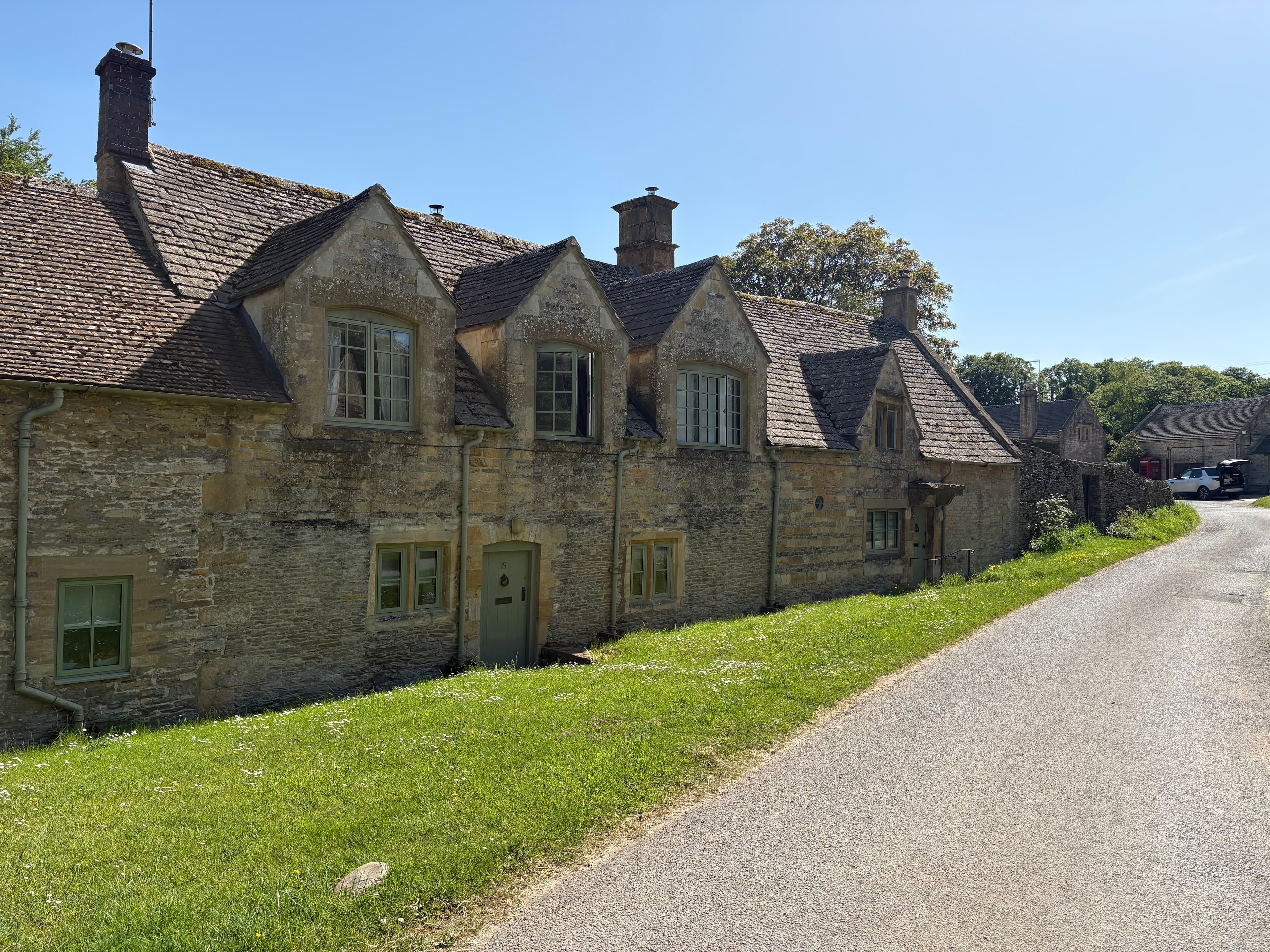 A row of dormer-windowed Cotswold-stone cottages along the lane through Notgrove