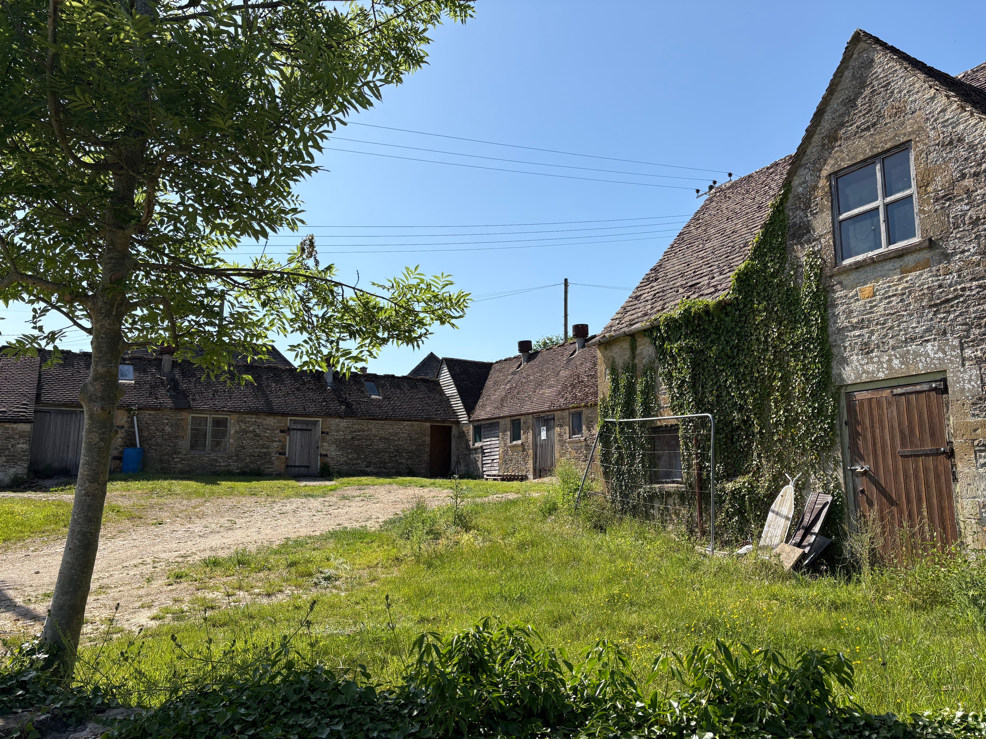A traditional Cotswold farmyard at Notgrove — ivy-clad barn, working sheds and an open yard
