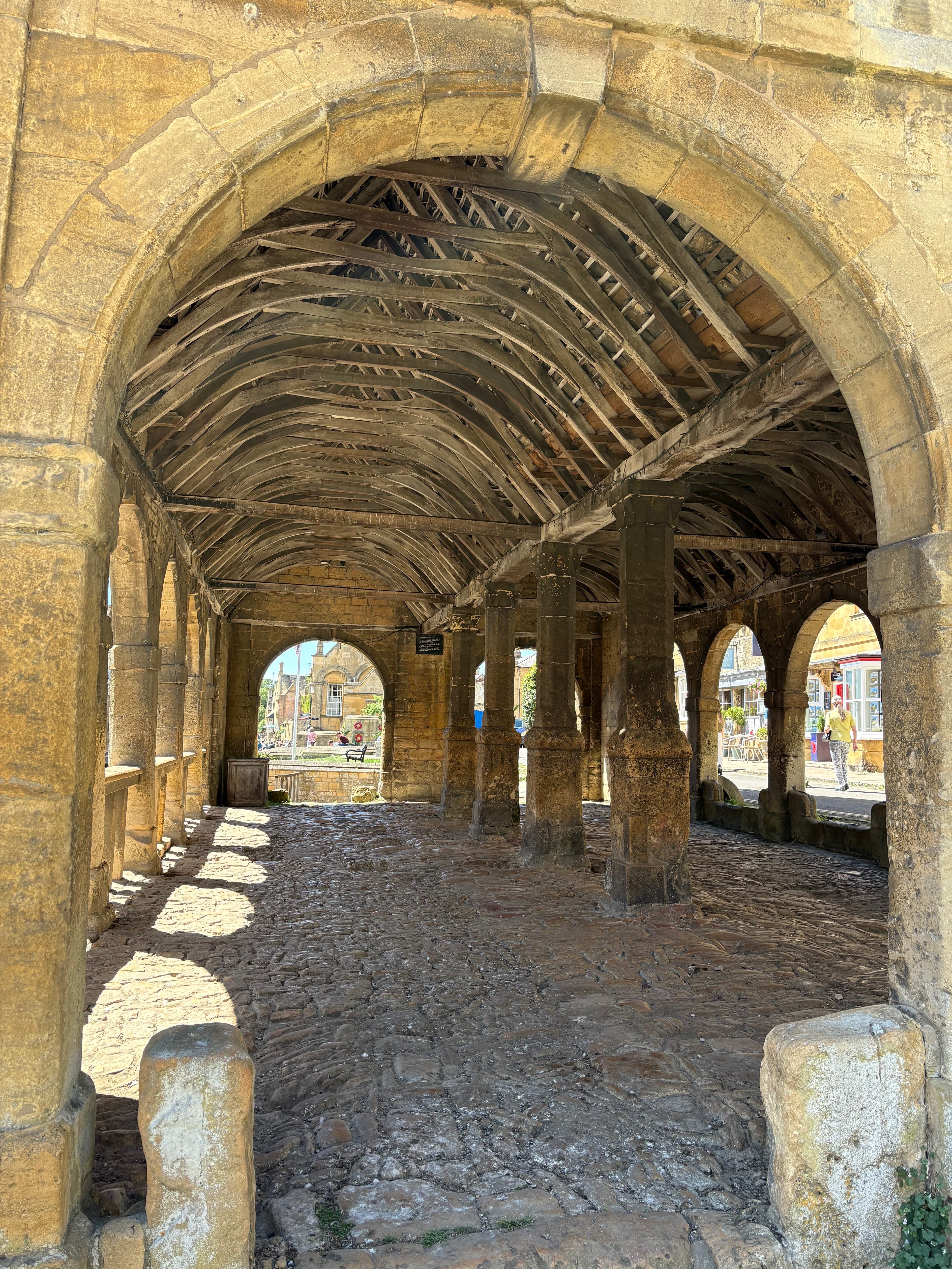 Looking up at the curved oak roof timbers of the Market Hall — a 17th-century timber-framed ceiling above the stone arcade