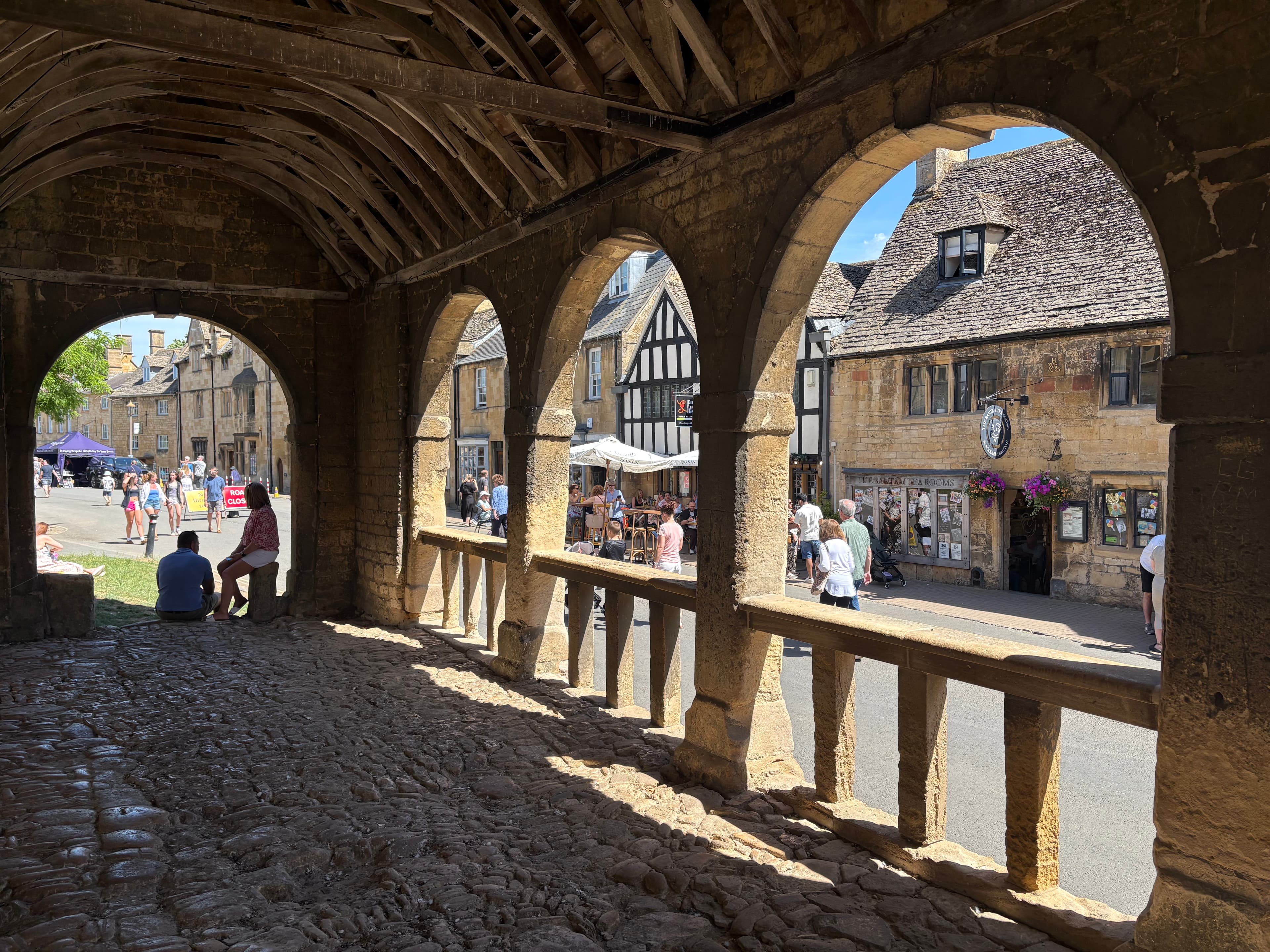 Looking out from inside the Market Hall through its stone arches to a timber-framed high-street building beyond