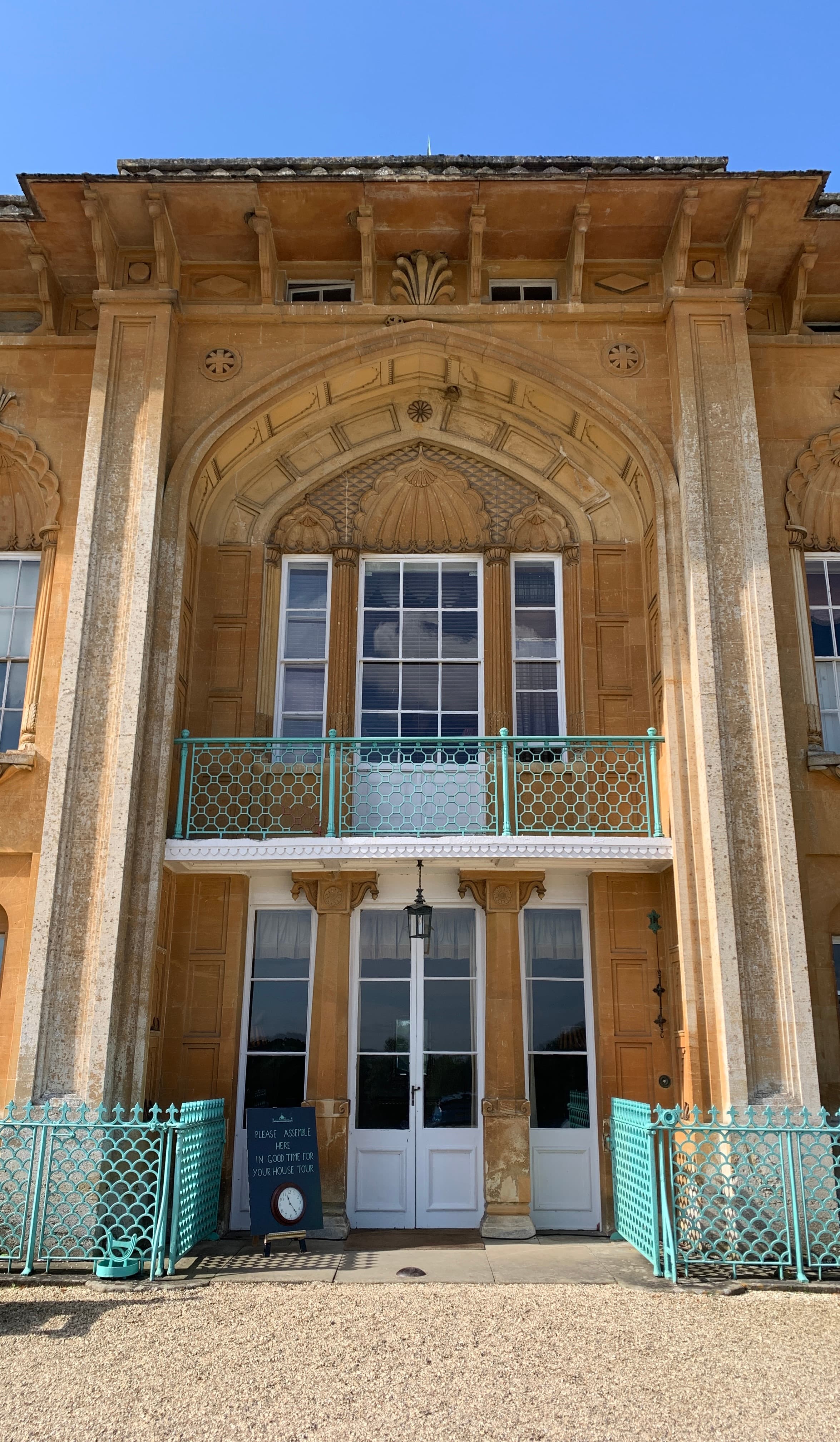 Close-up of Sezincote's south facade — Indian-style stonework, an ogee arch and a turquoise wrought-iron balcony rail
