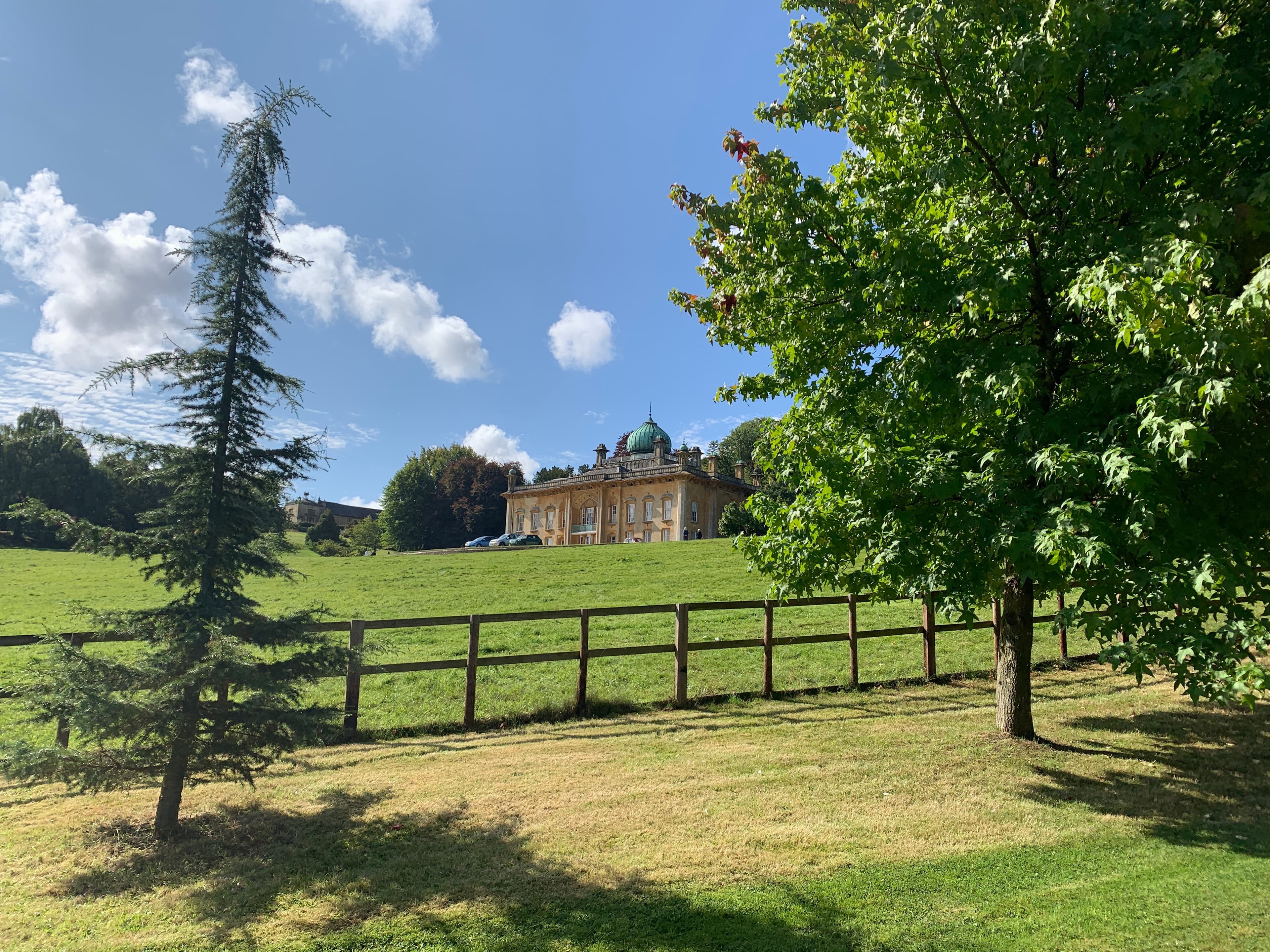 Sezincote's Mughal-style cupolas across the parkland, framed by mature trees and a wooden post-and-rail fence