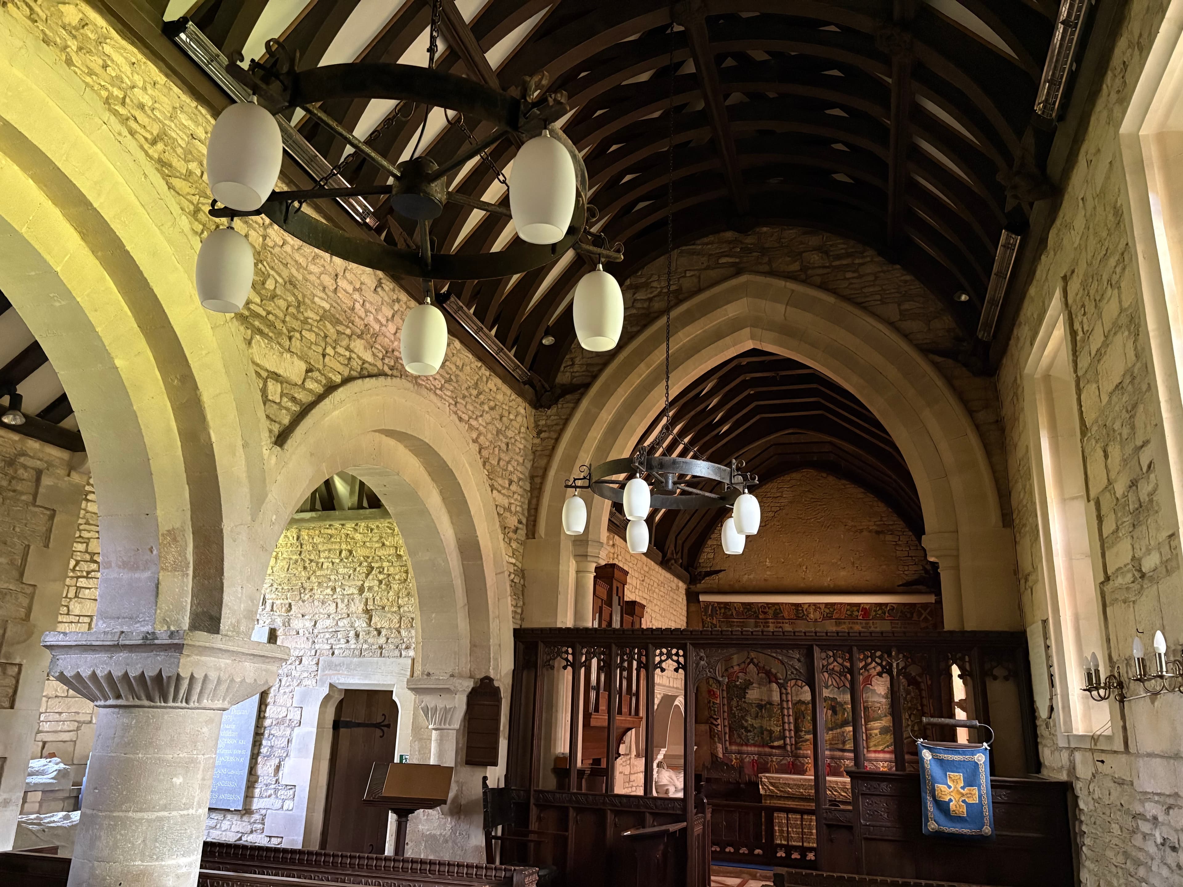 Inside St Bartholomew's — Norman arches, timbered roof and pendant glass lights down the nave