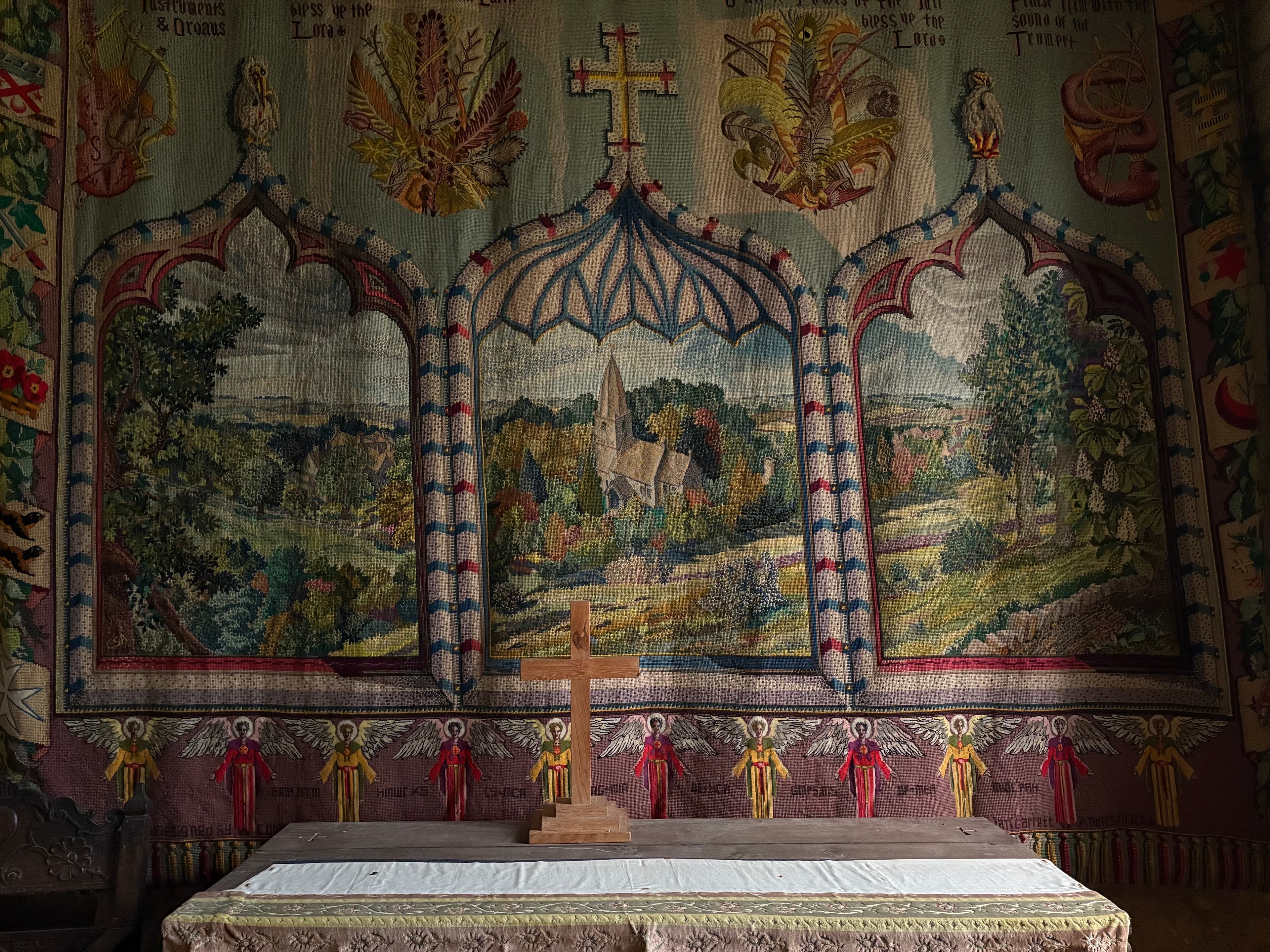 The painted reredos above the altar at St Bartholomew's — landscape panels of the church set into Gothic ogee arches, with a row of angels along the bottom
