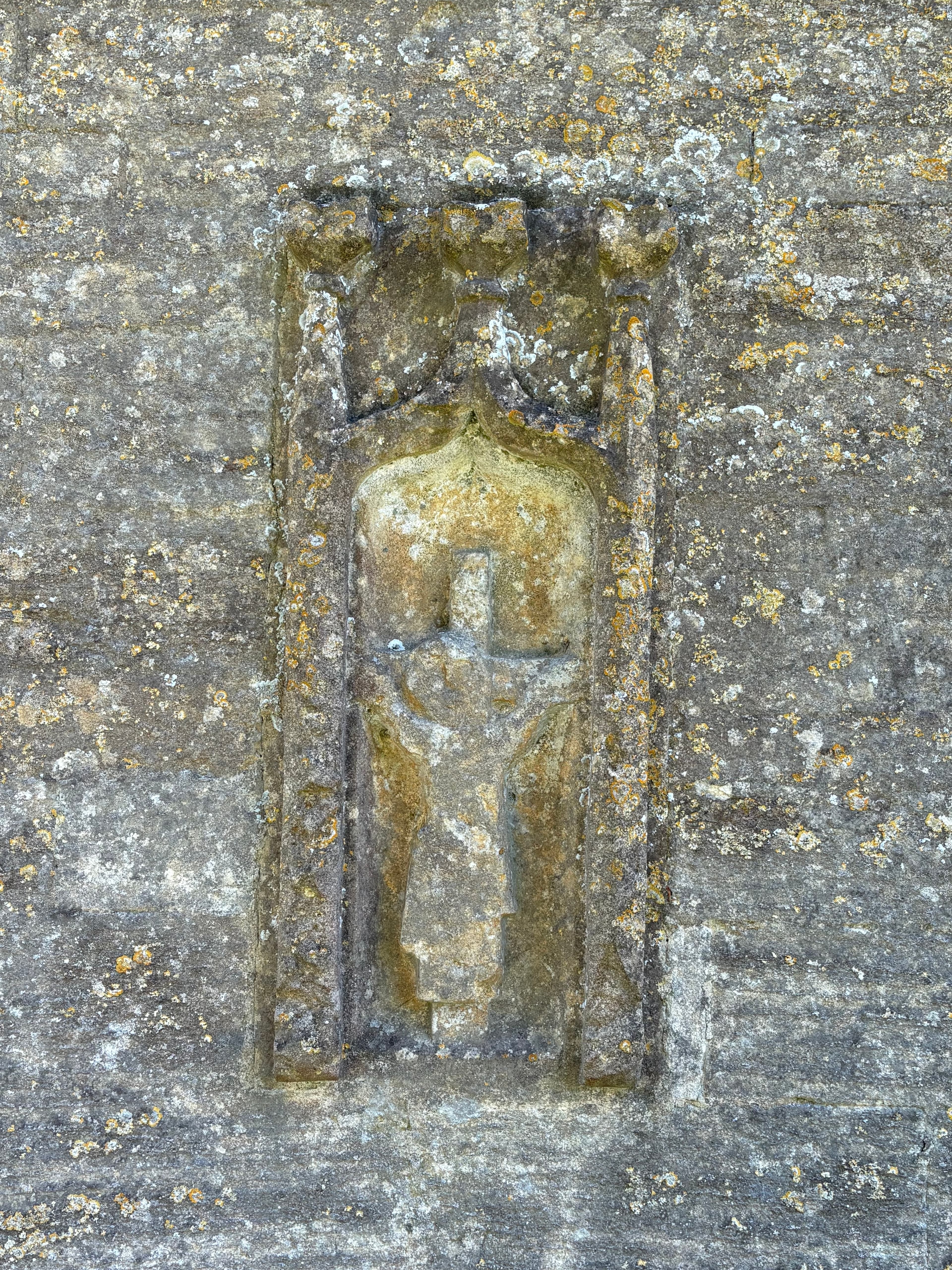 A weathered carved stone effigy of a Whittington family member set into the wall of St Bartholomew's
