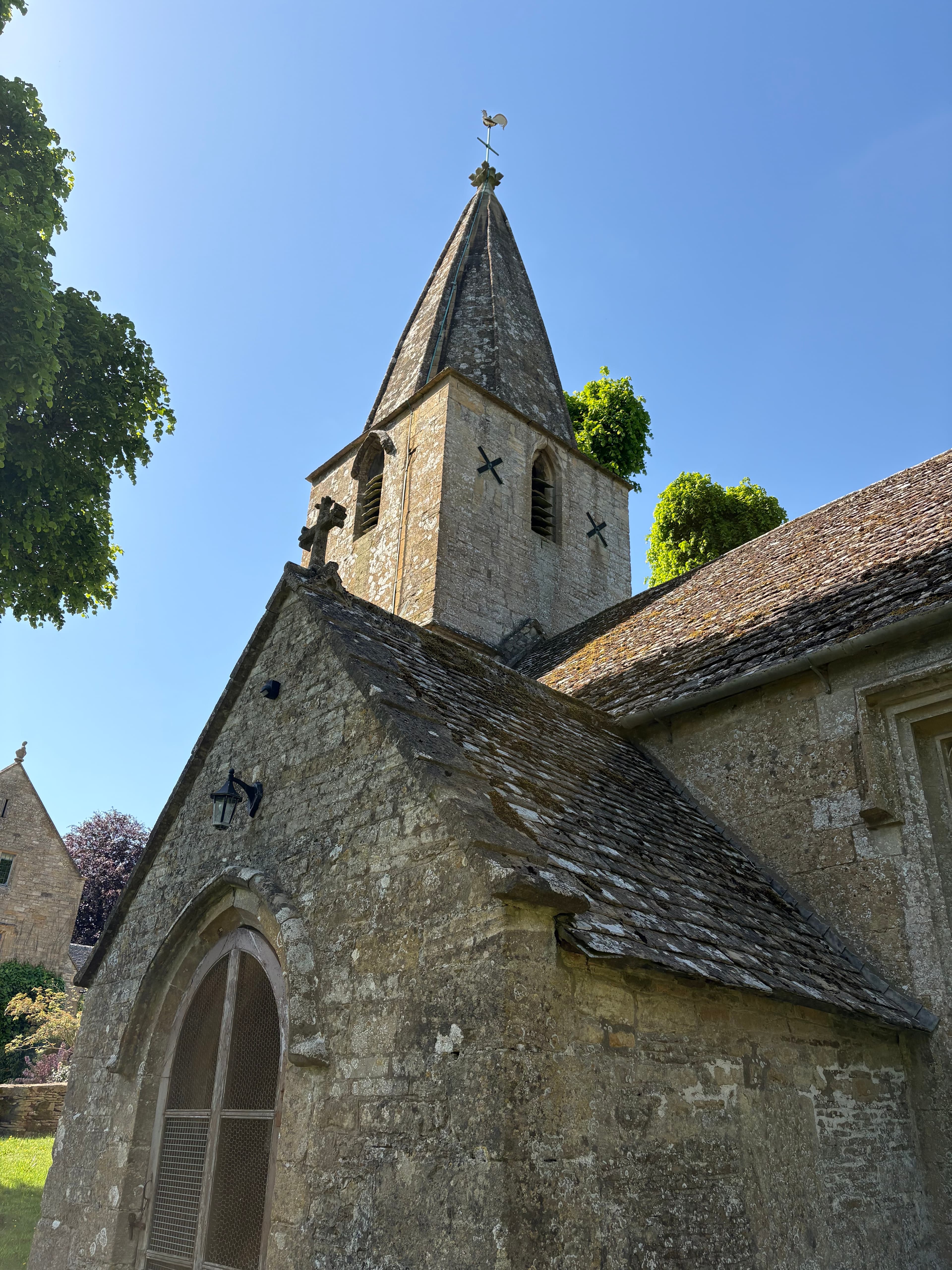 Looking up at the tower and short spire of St Bartholomew's with its gilded weathercock