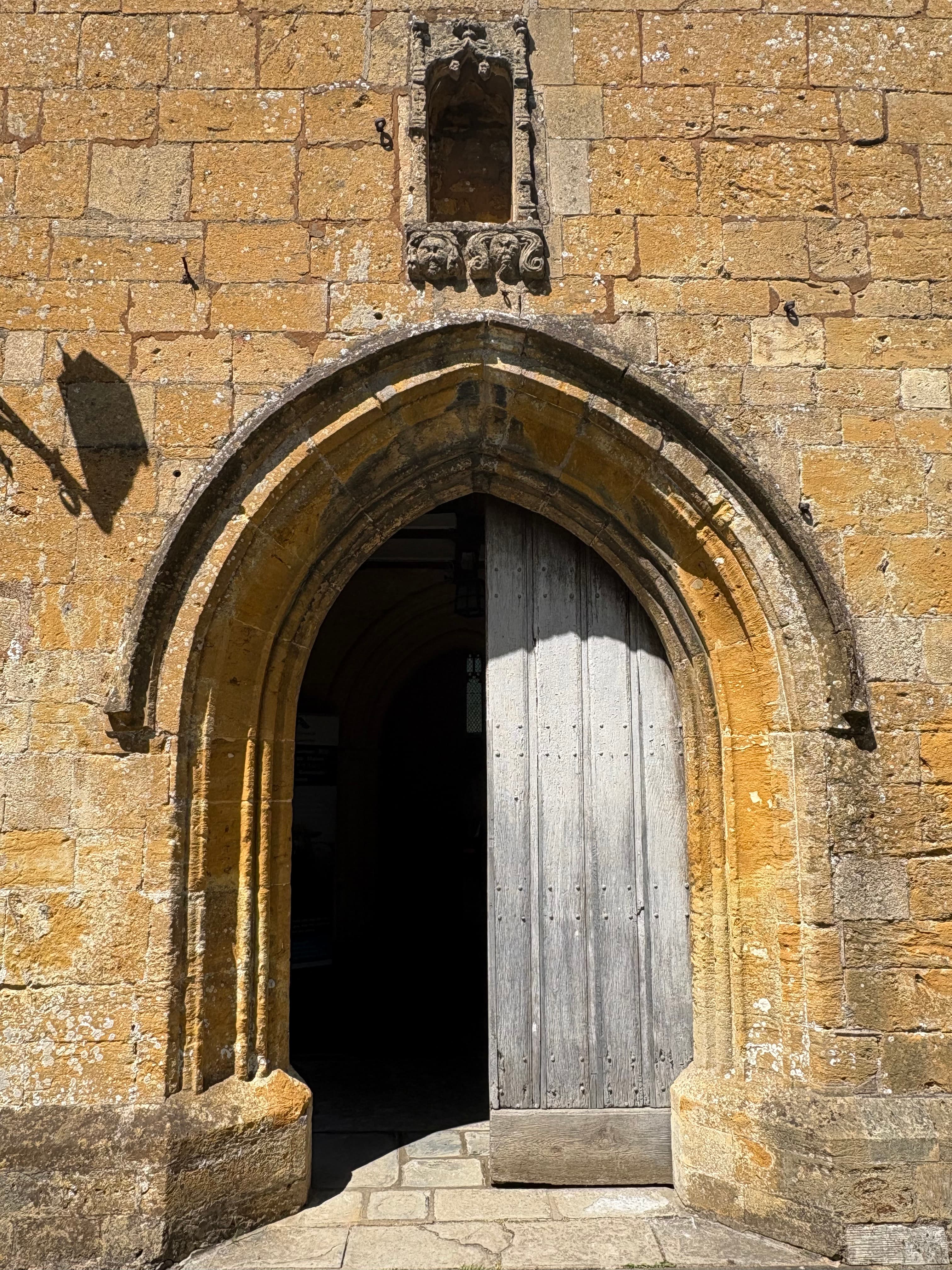Close-up of one of St James's stone-arched doorways with its weathered wooden door beneath