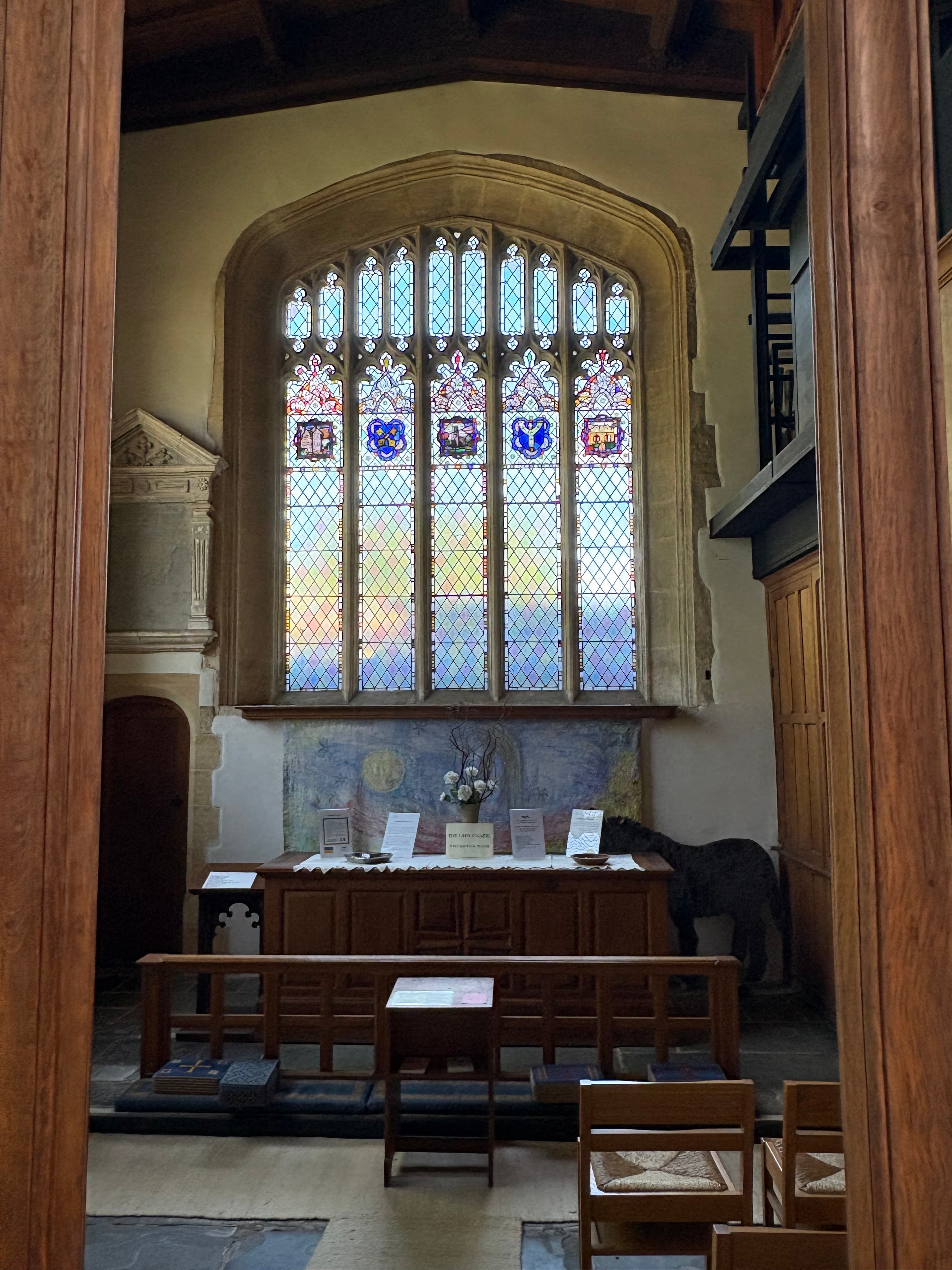 A medieval stained-glass window in a side chapel at St James's, with leaded panels of saints and heraldic shields