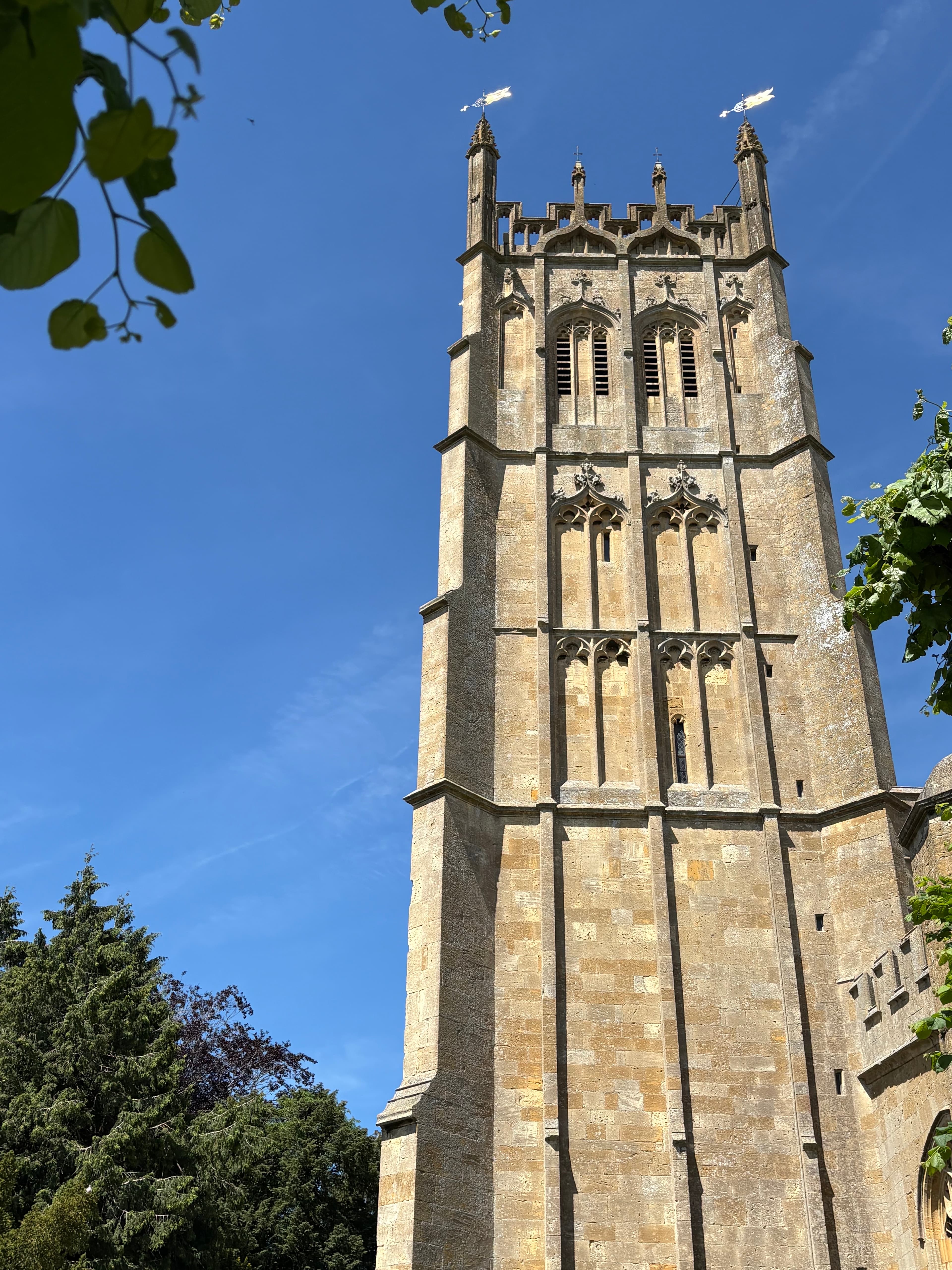 Looking up at the tall Perpendicular tower of St James's — twin belfry openings, traceried windows and crenellated parapet