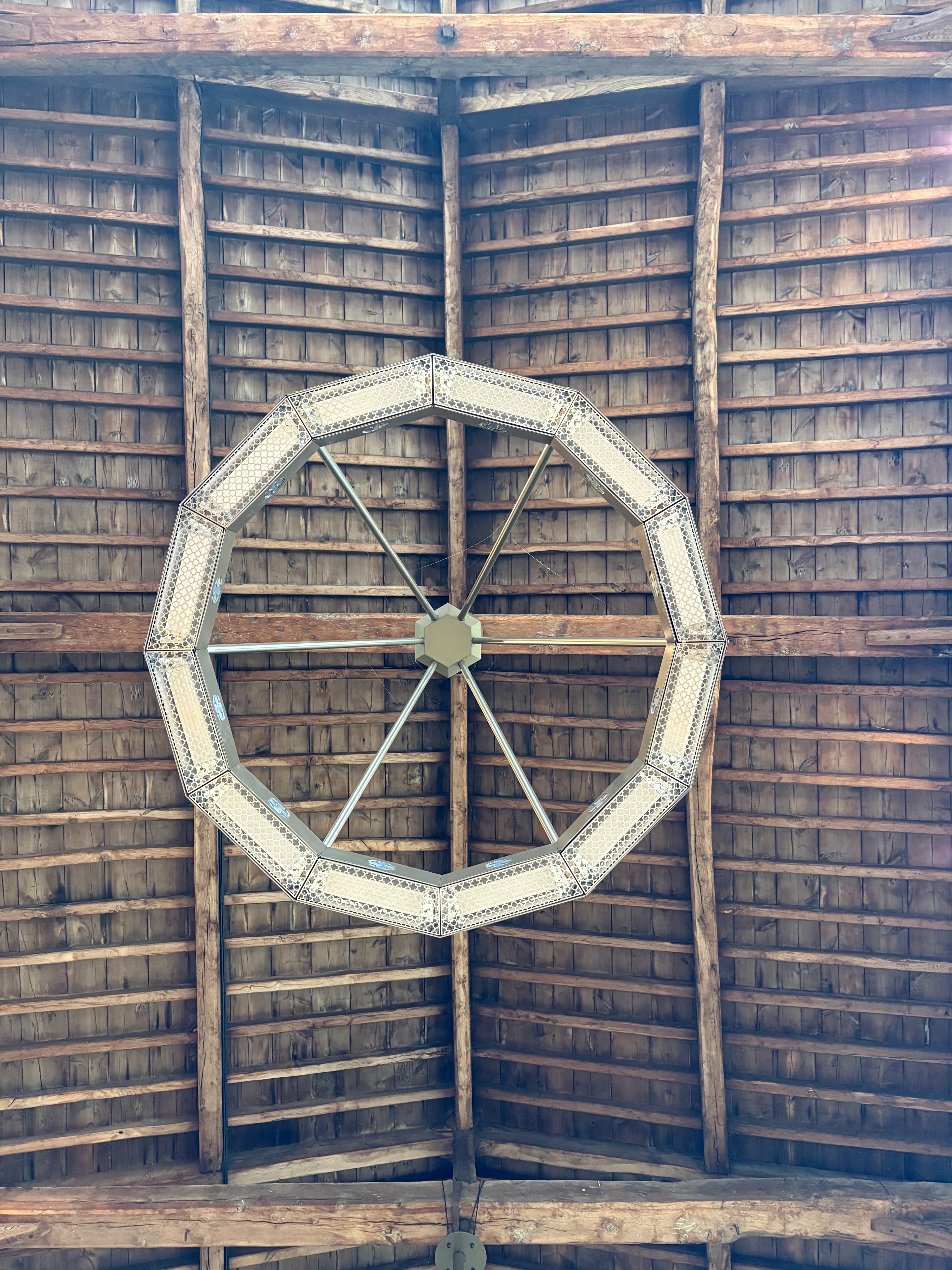 A polygonal hoop chandelier suspended from the timbered roof