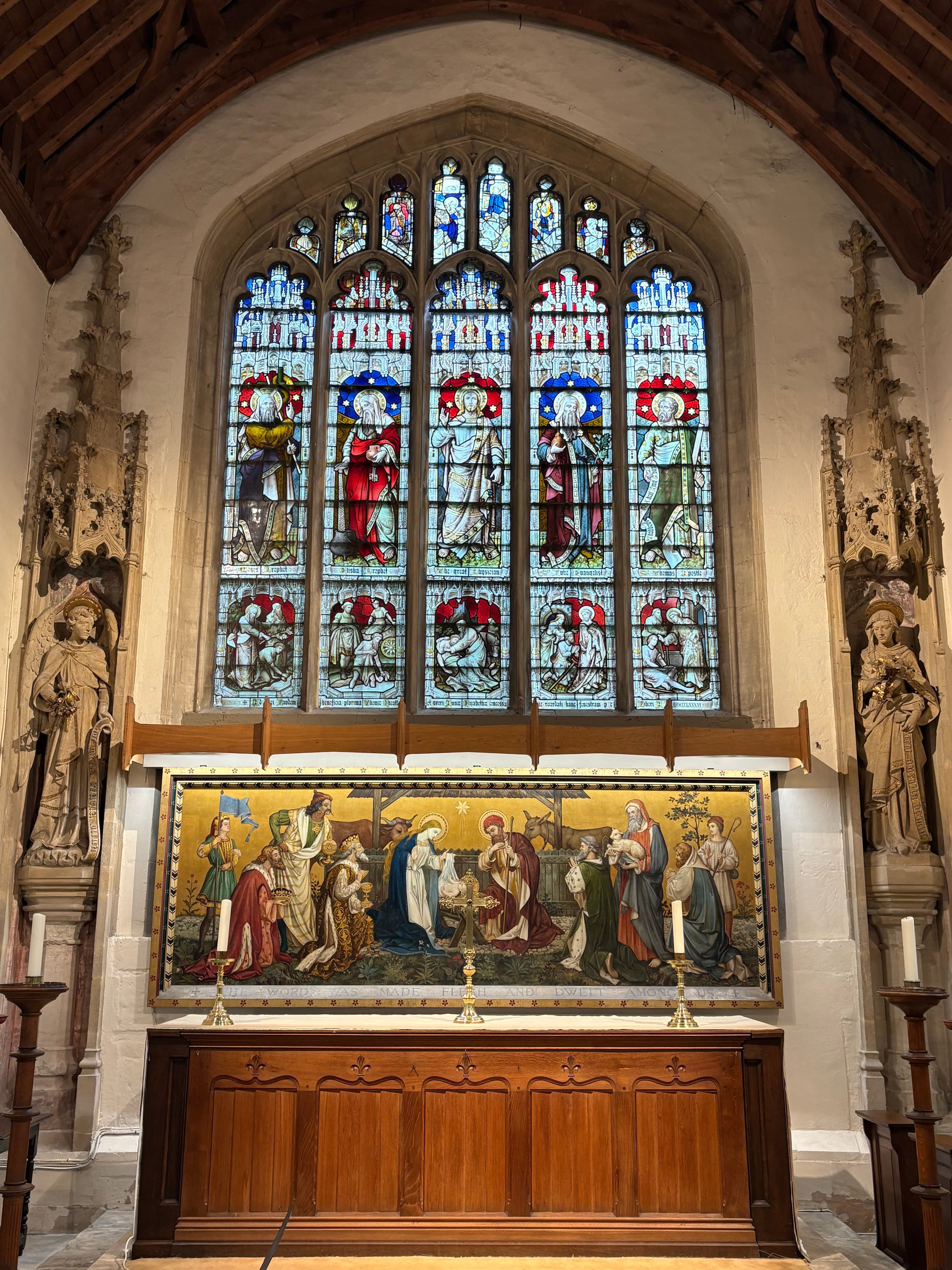 The east window above the altar — five-light stained glass and an embroidered altar frontal