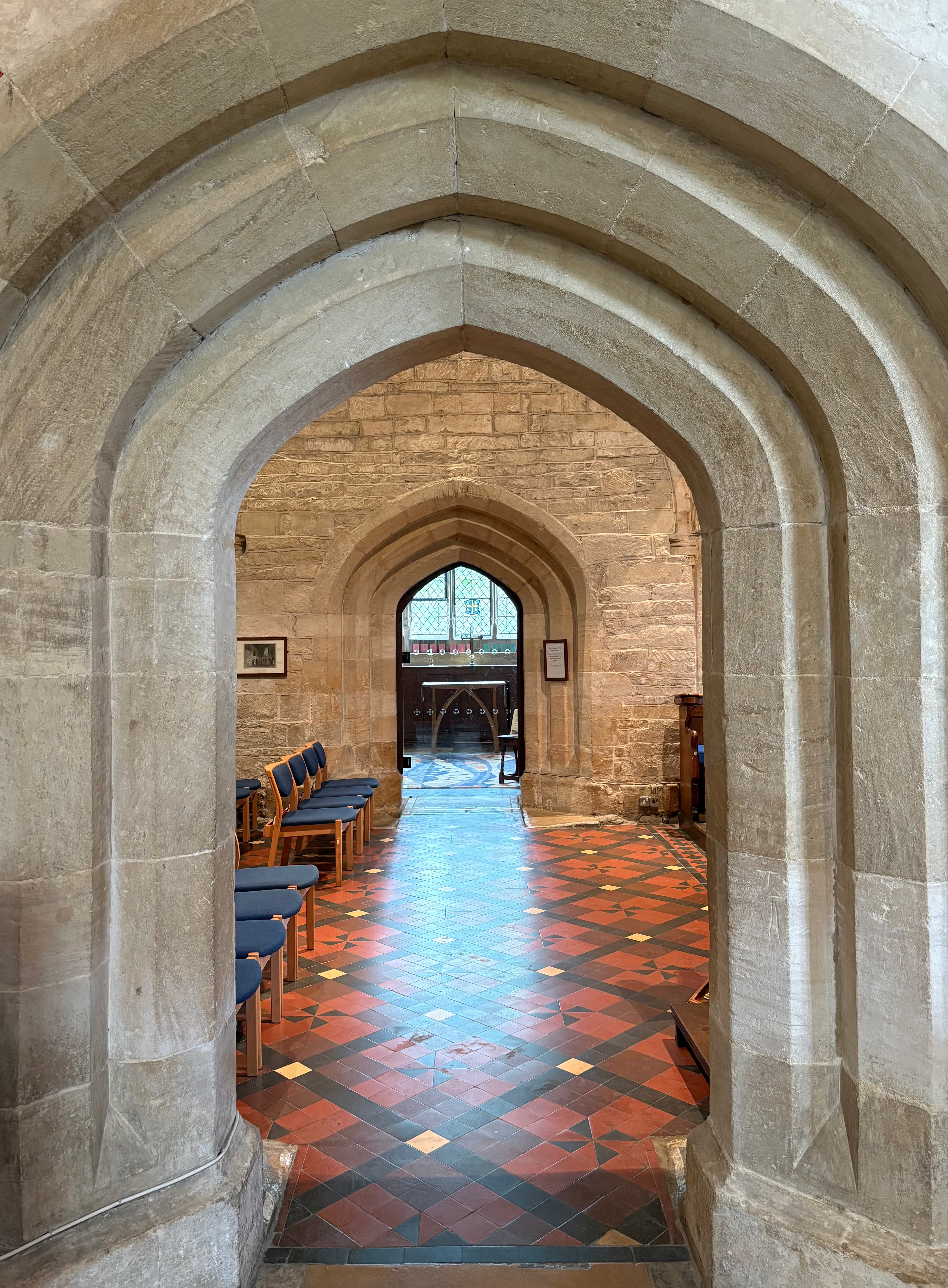 A stone archway looking down the nave, tiled floor leading toward a far doorway
