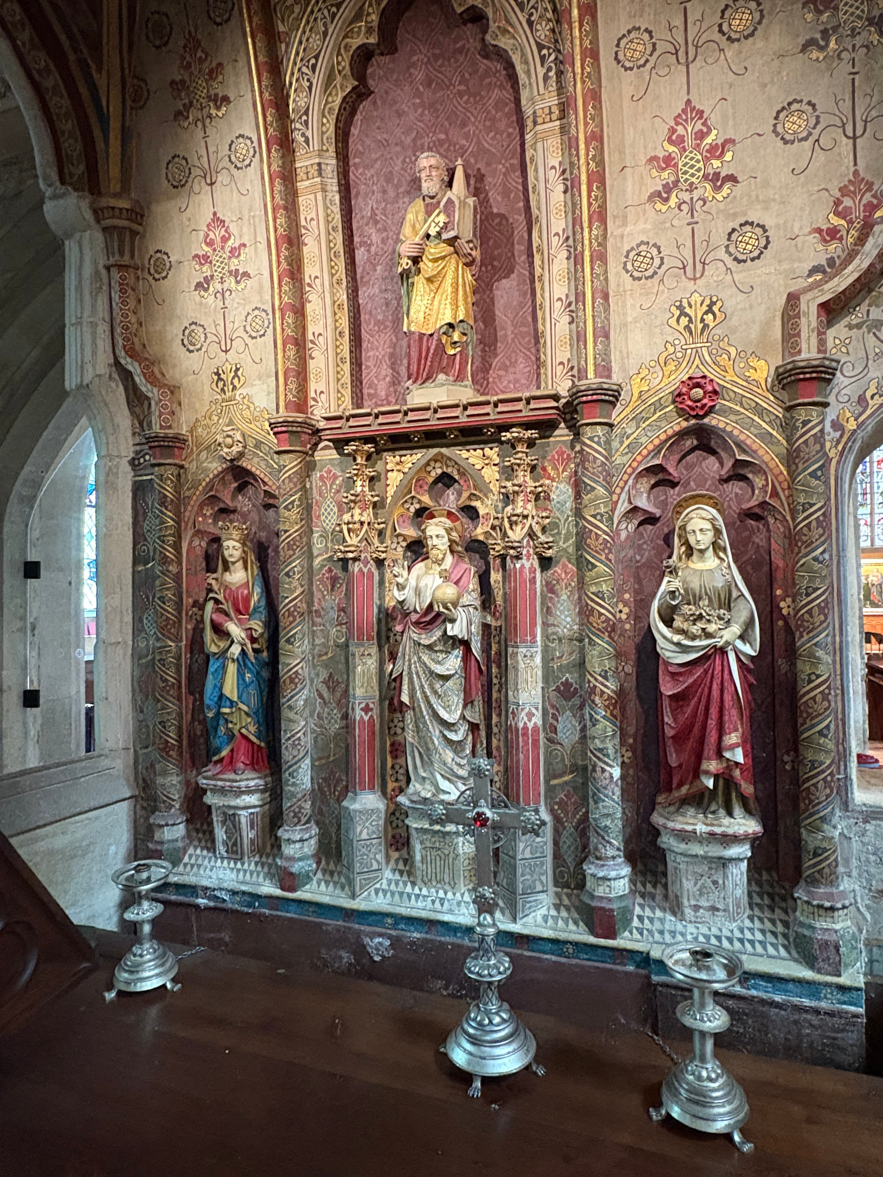 A painted reredos detail — gilded statues set against a richly patterned panelled wall