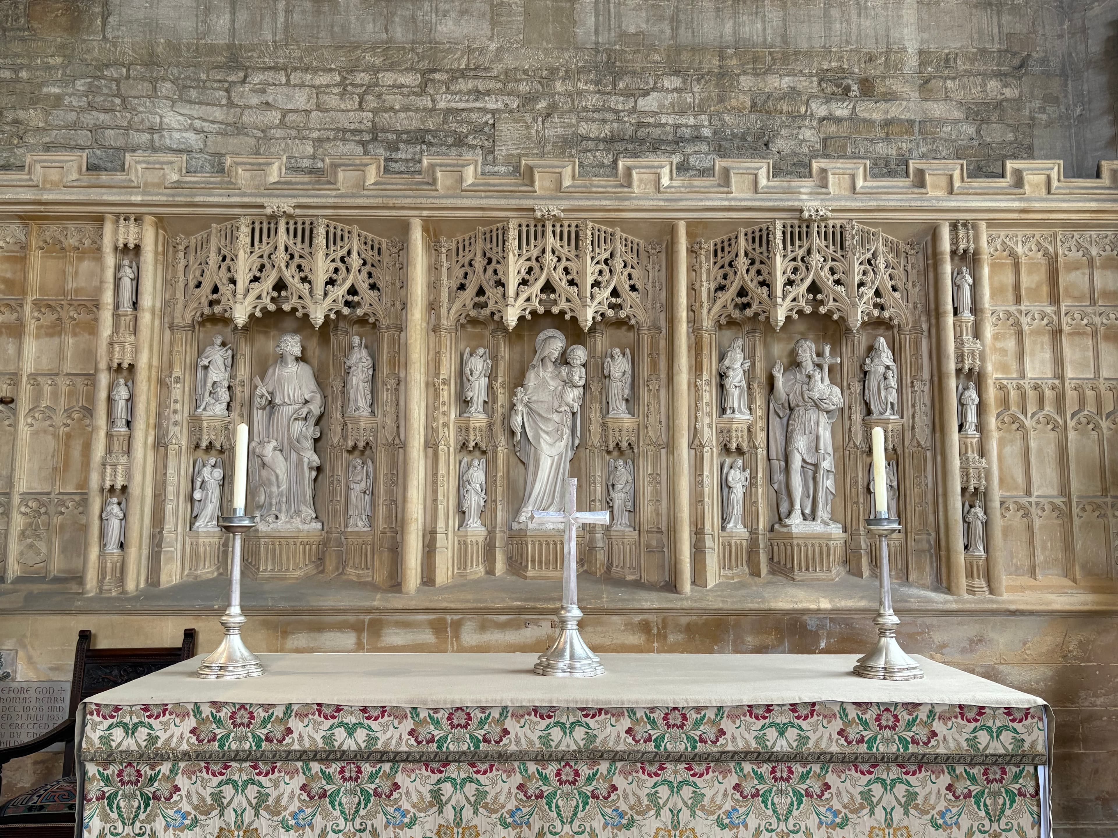 The carved stone reredos behind the altar, with statues in gothic canopied niches