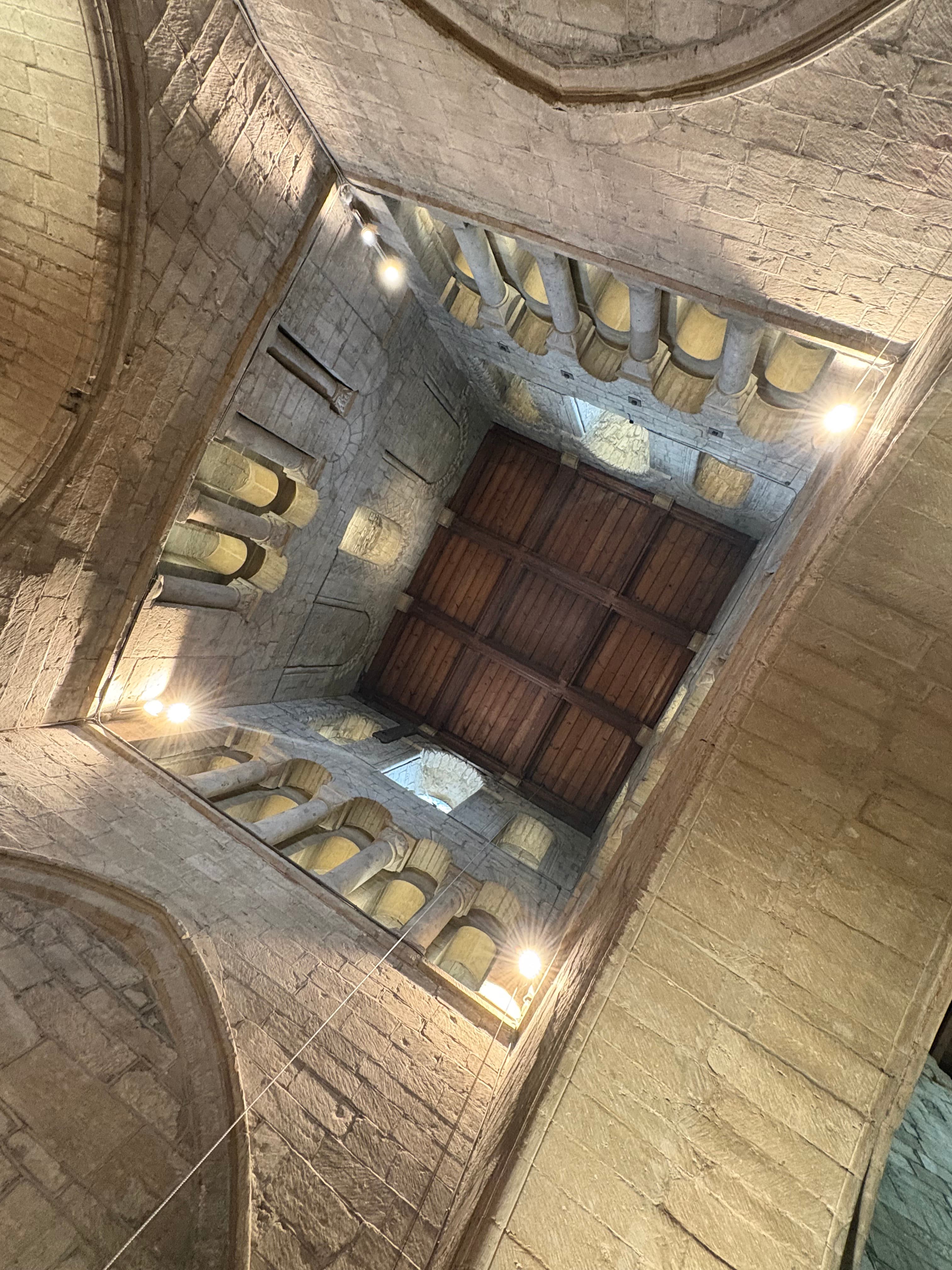 Looking straight up into the tower vault — Norman arches and a timbered ceiling