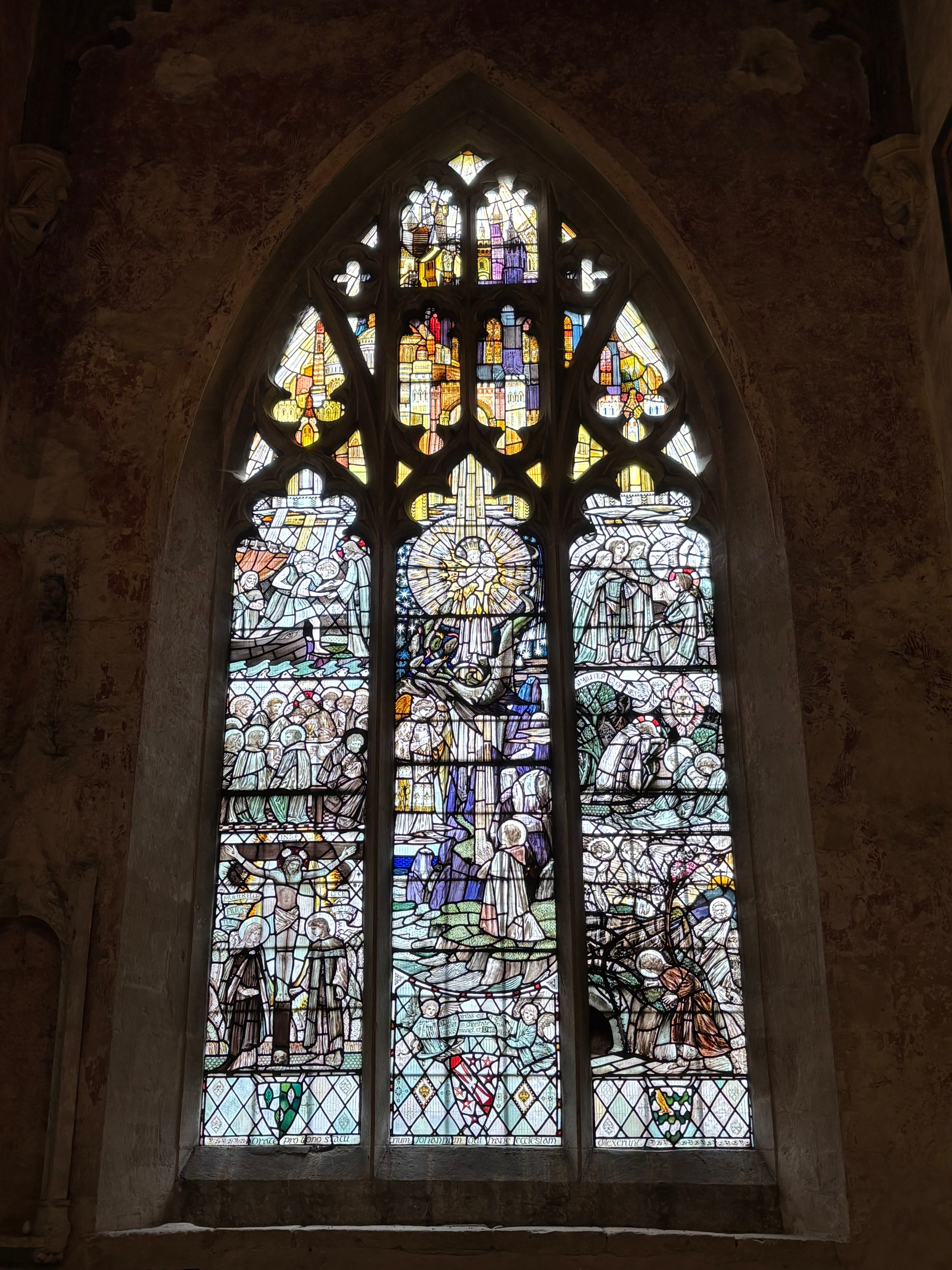 Another arched stained-glass window framed by the church's pale limestone walls