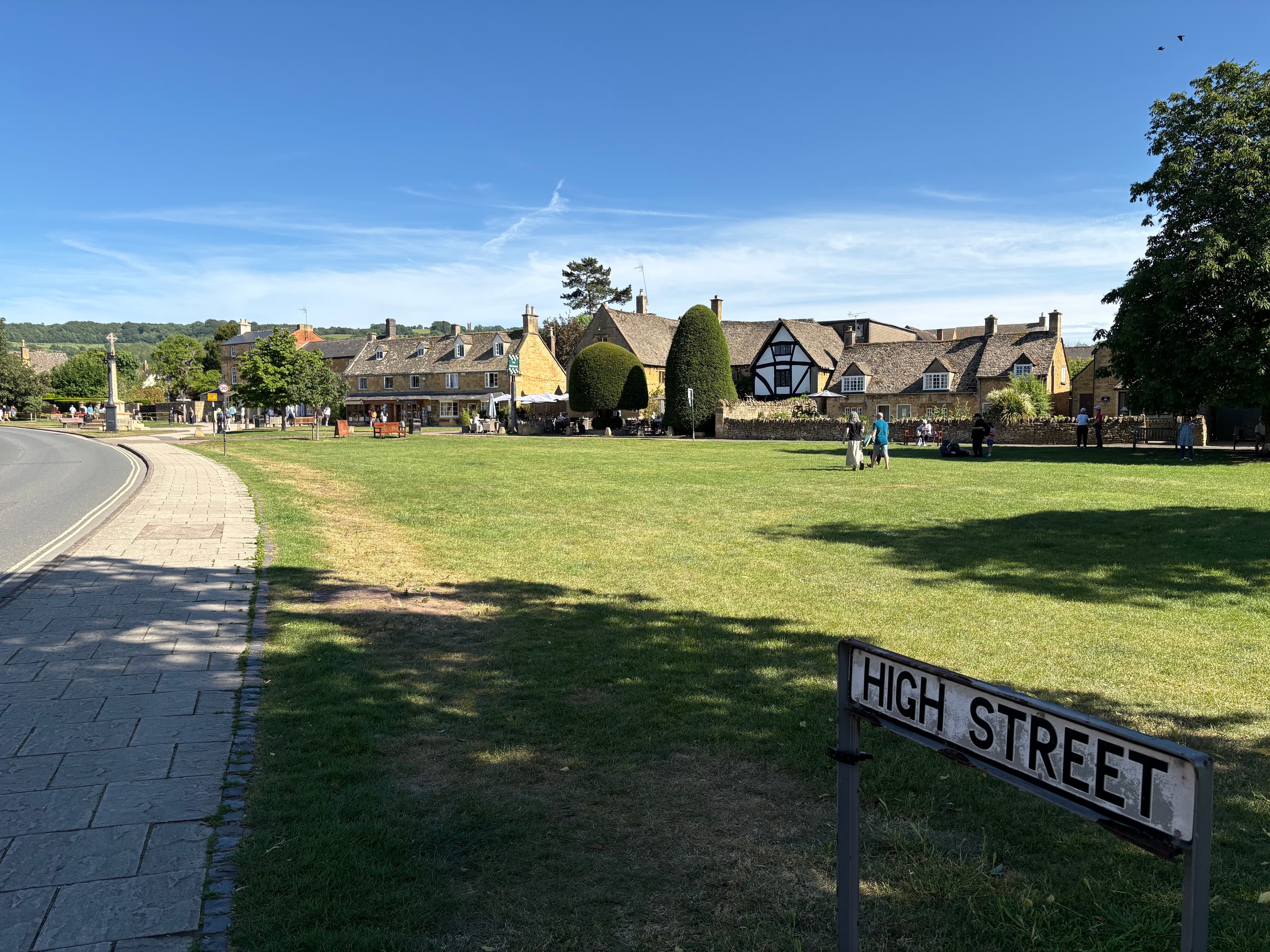 The 'High Street' sign in the foreground, with Broadway's wide green and the village beyond