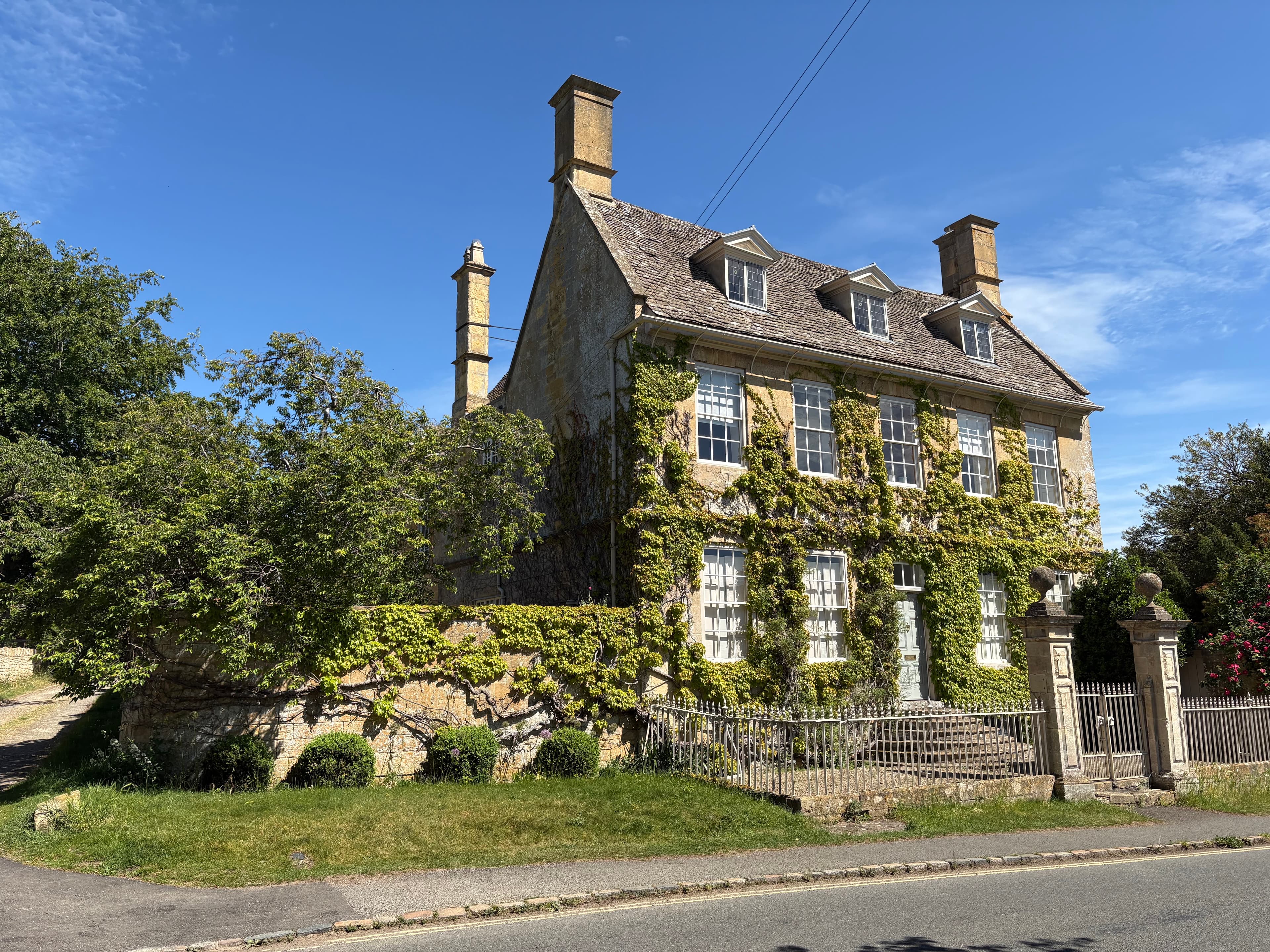 An imposing three-storey Cotswold manor house in Broadway clad in ivy