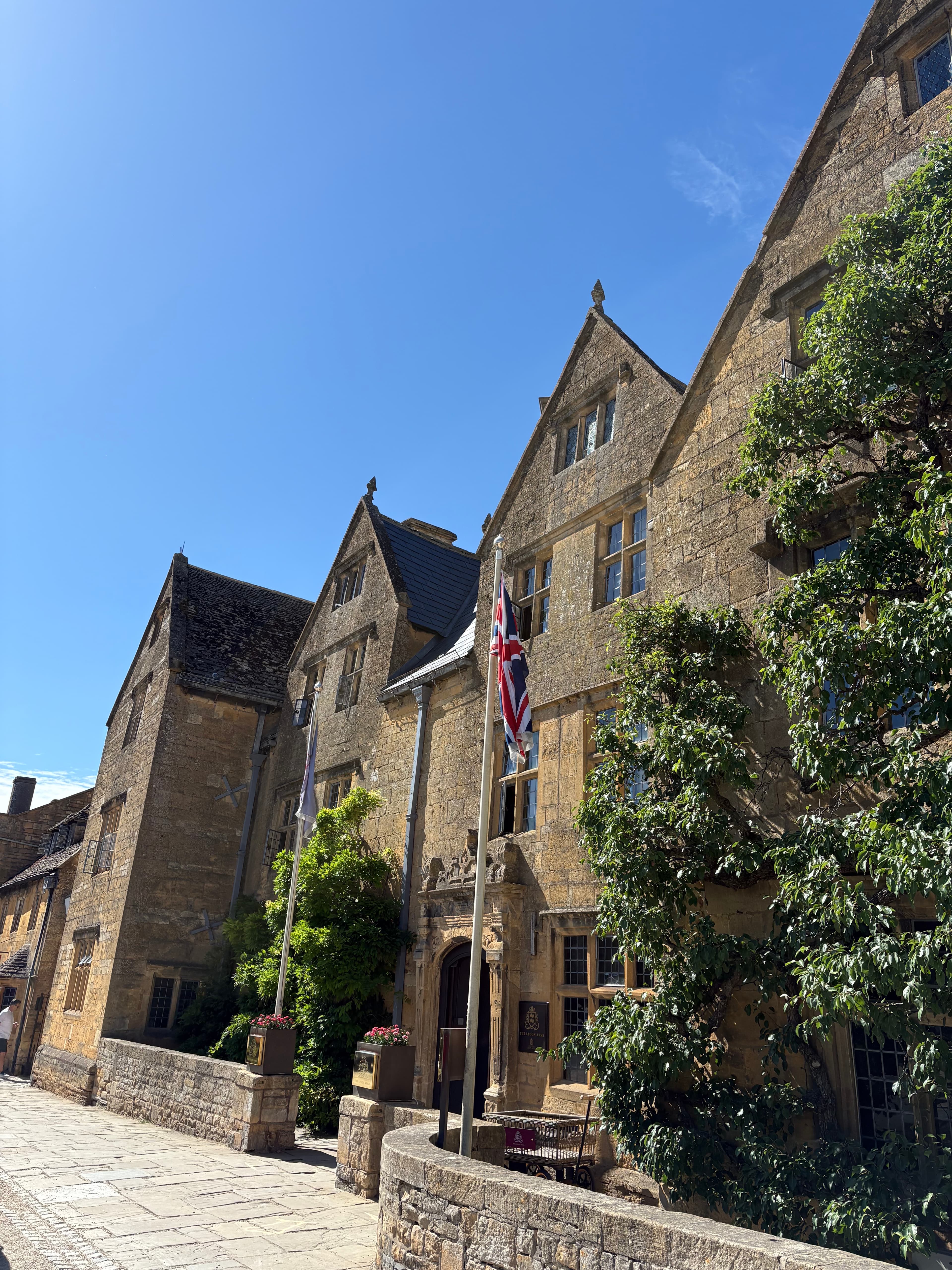 The Lygon Arms clock tower and Union Jack flag in front of mature trees