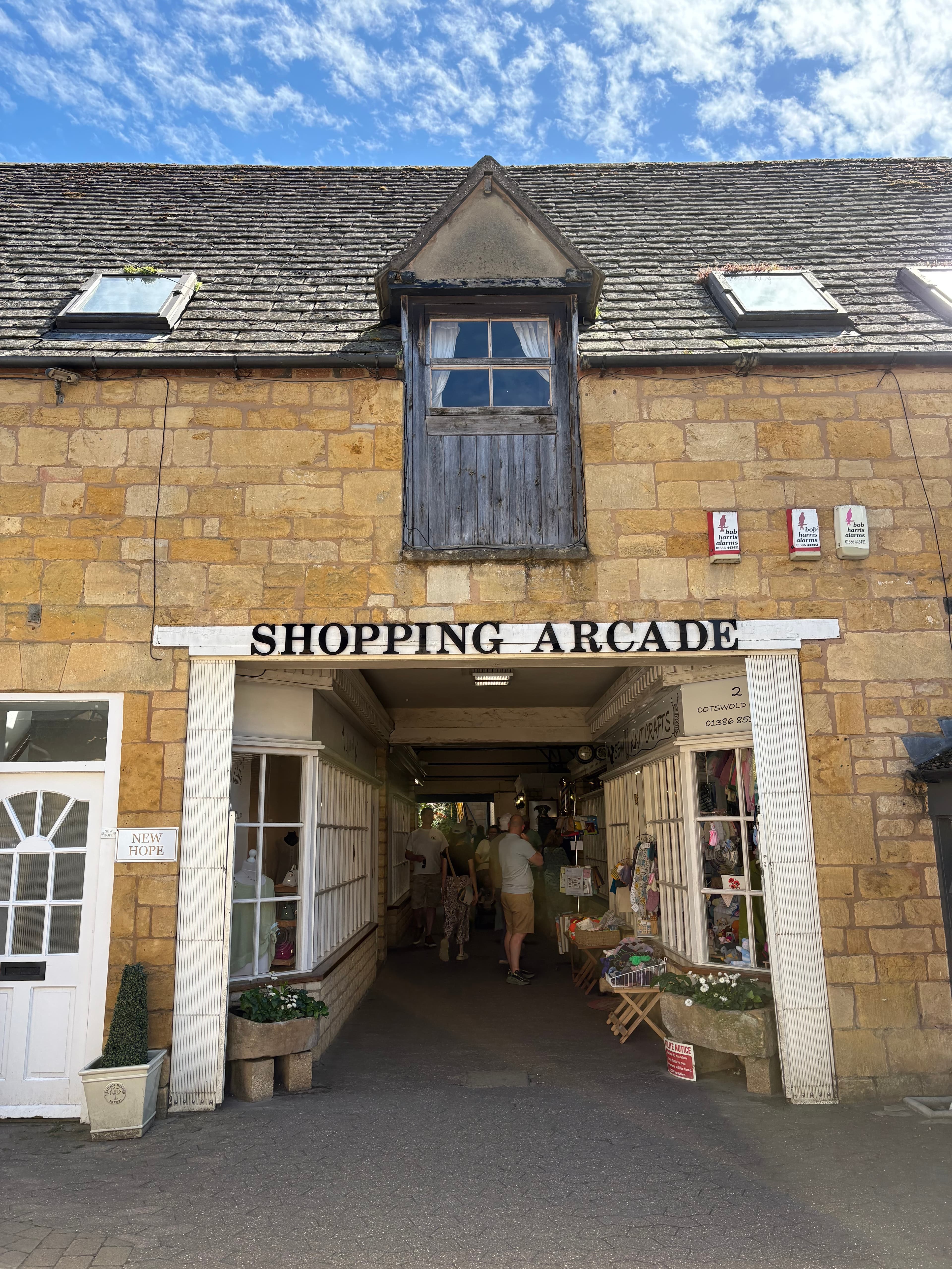 The 'Shopping Arcade' entrance — a covered passageway between Cotswold-stone shopfronts
