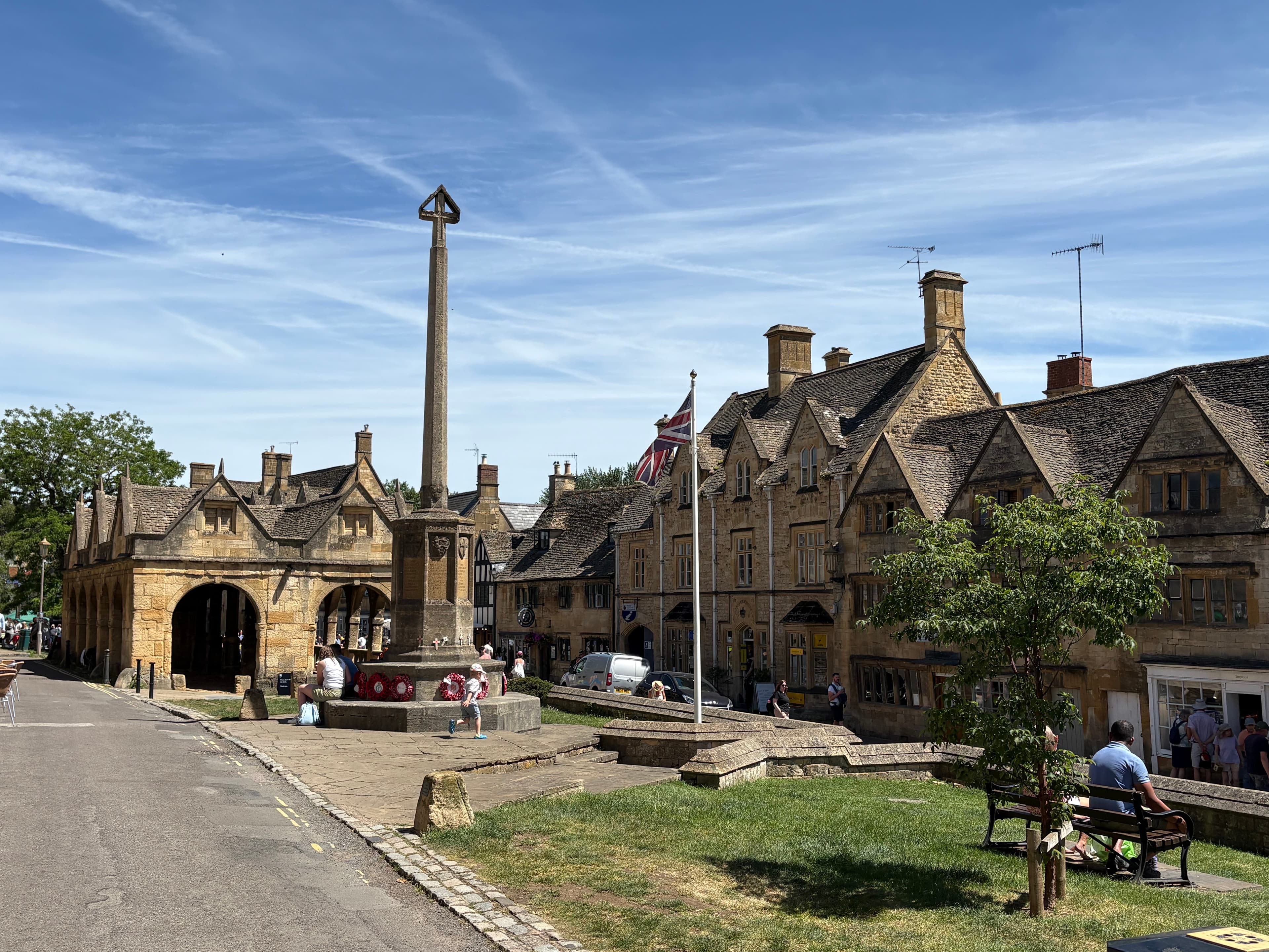 Wider view of the Market Hall with the war memorial cross in the foreground and the gabled high-street cottages behind