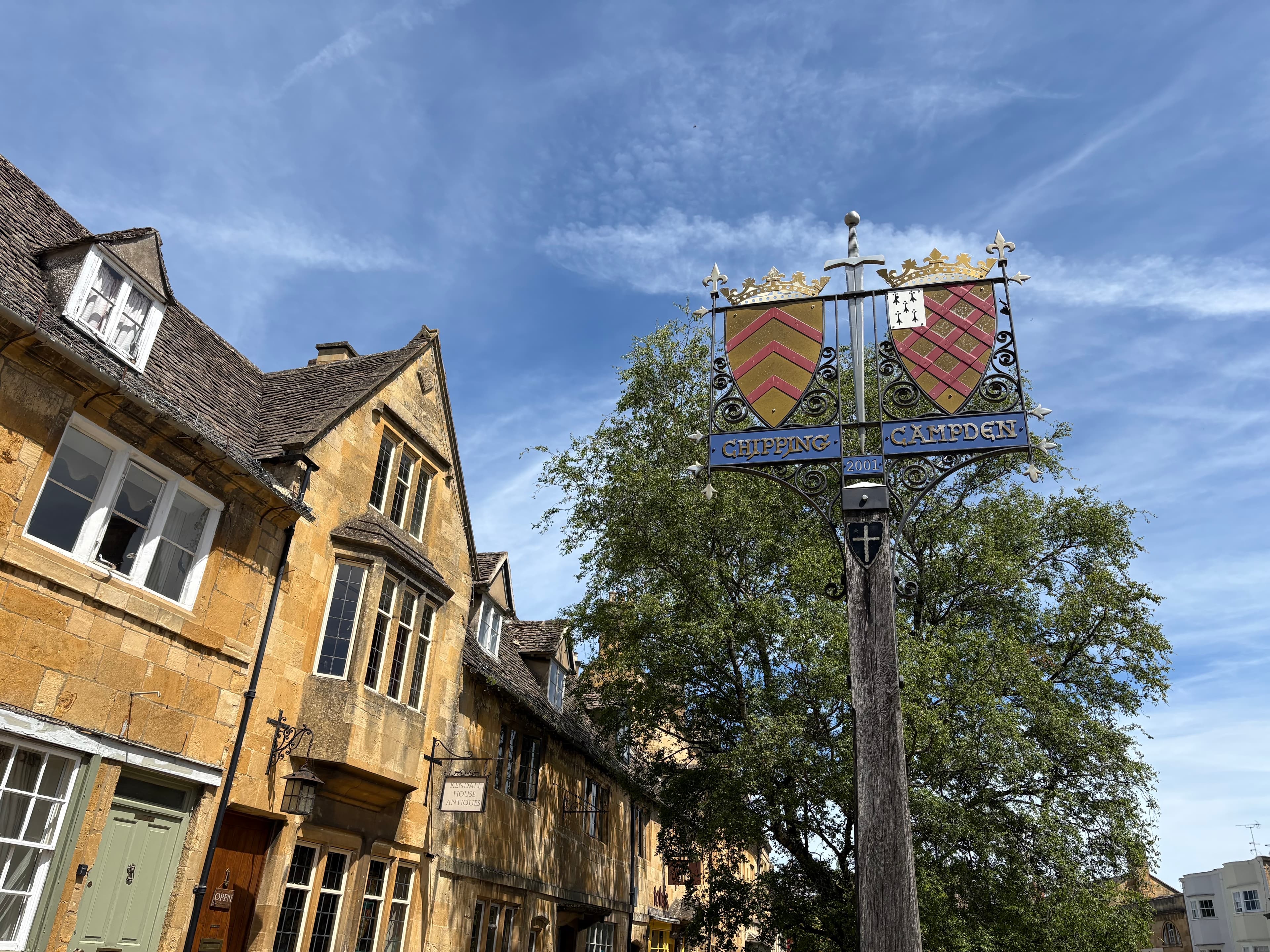 Chipping Campden's heraldic town sign with its painted shields, raised over the High Street