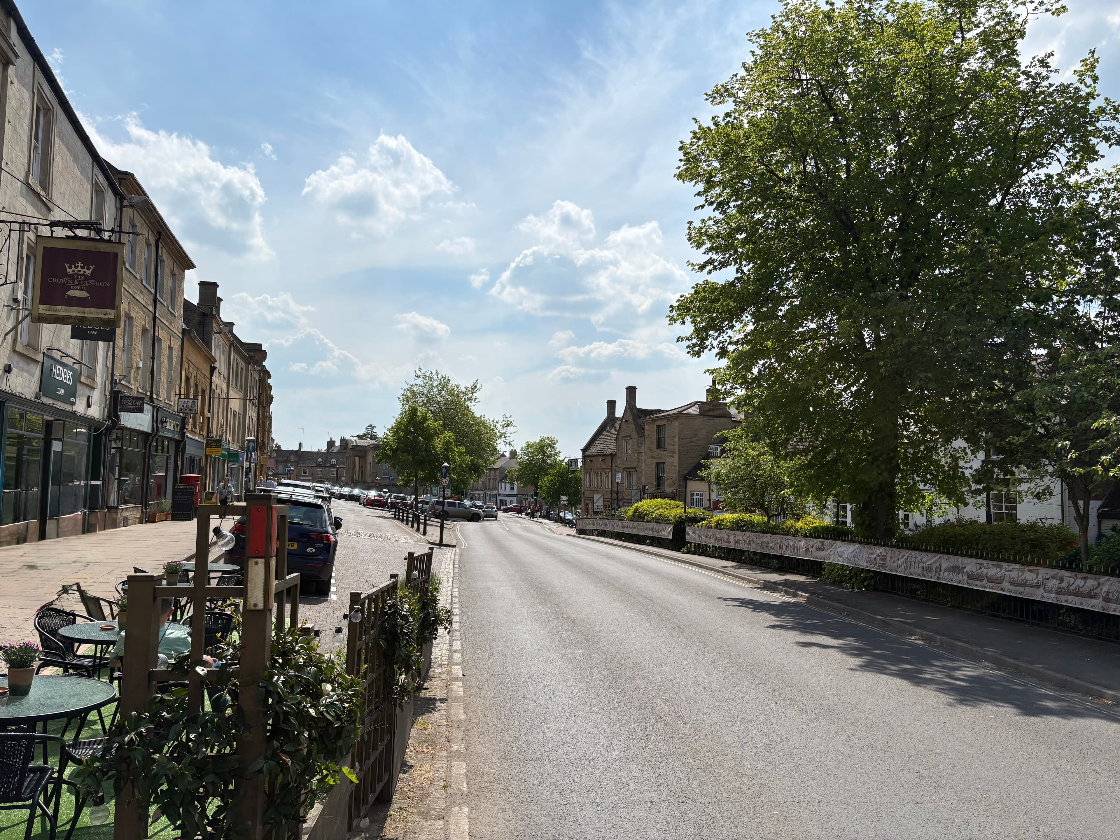 Looking down Chipping Norton's wide tree-lined high street on a sunny day