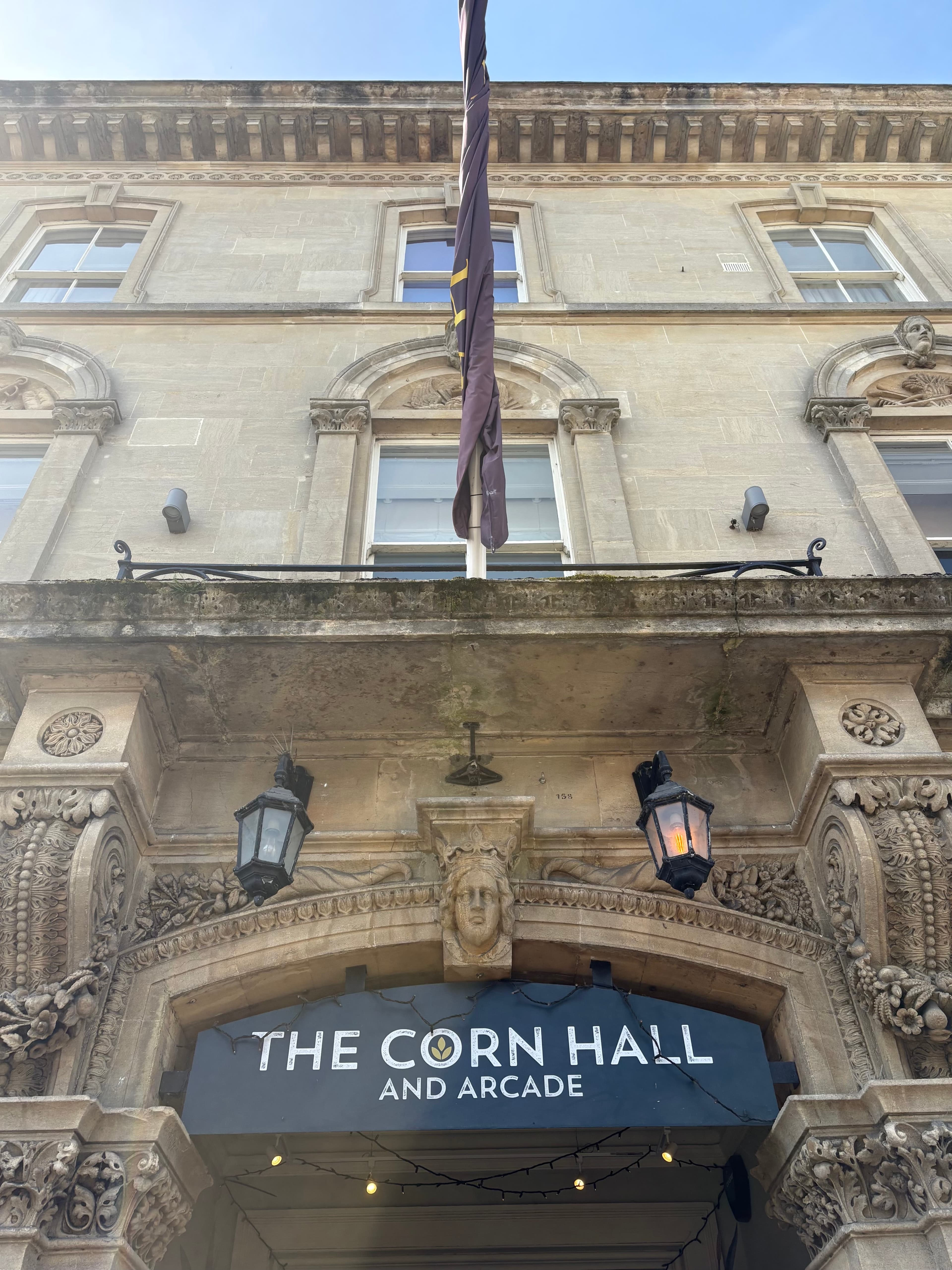 The Corn Hall entrance with carved stone lanterns either side and a flag overhead