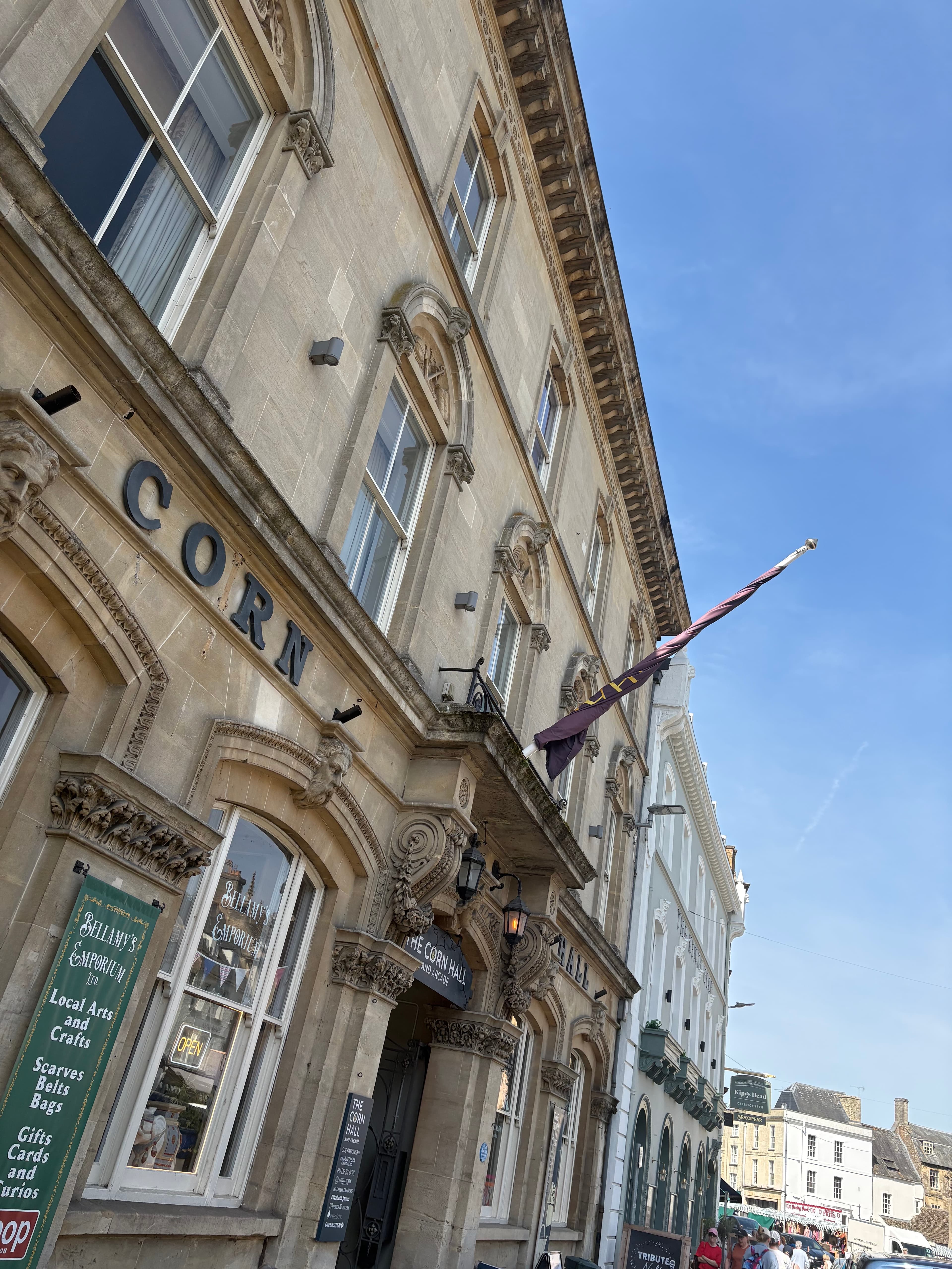 Looking up at the Corn Hall — carved stonework and a vertical purple-and-cream flag