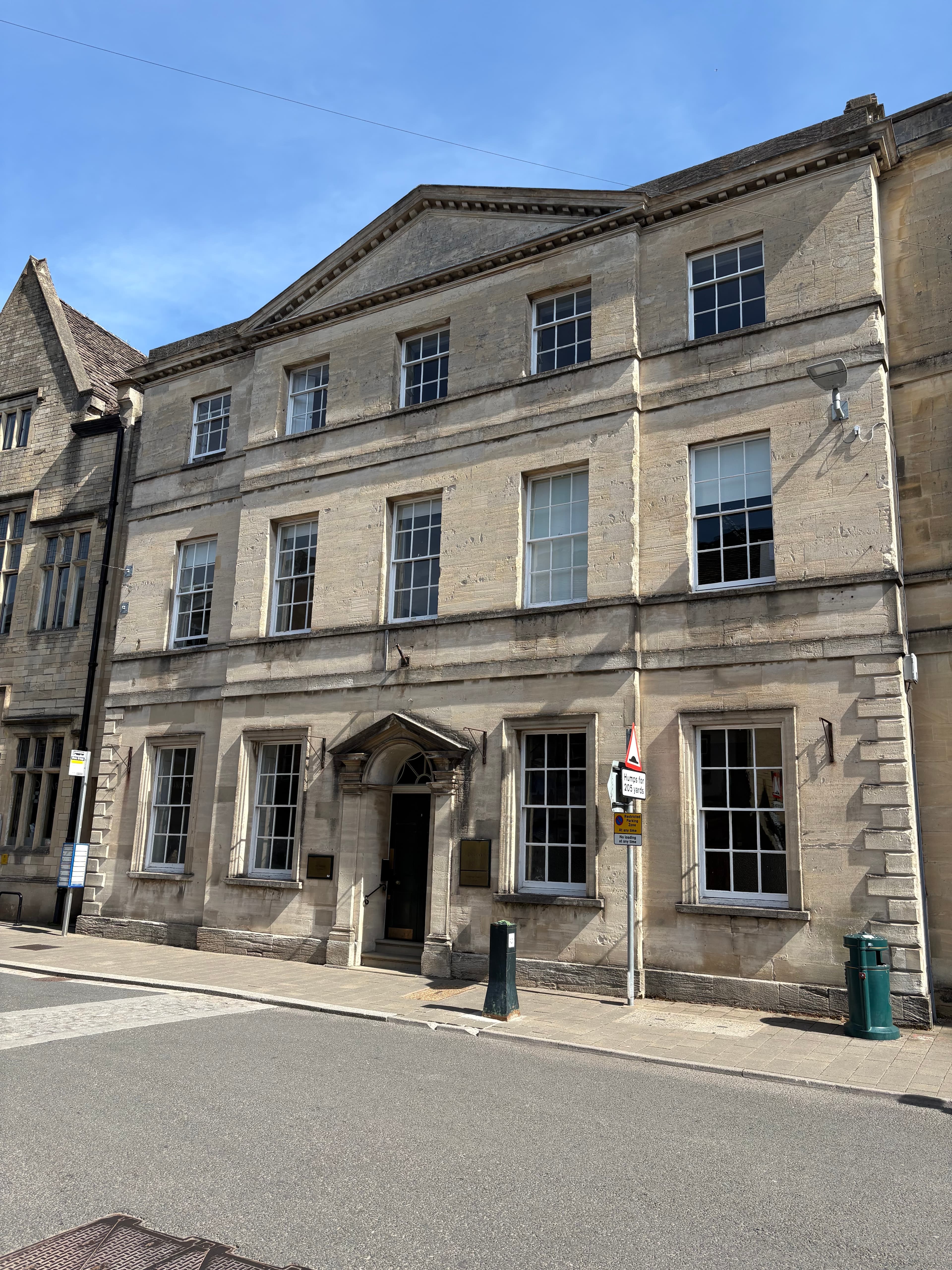 A tall Cotswold-stone Georgian building on a Cirencester side street