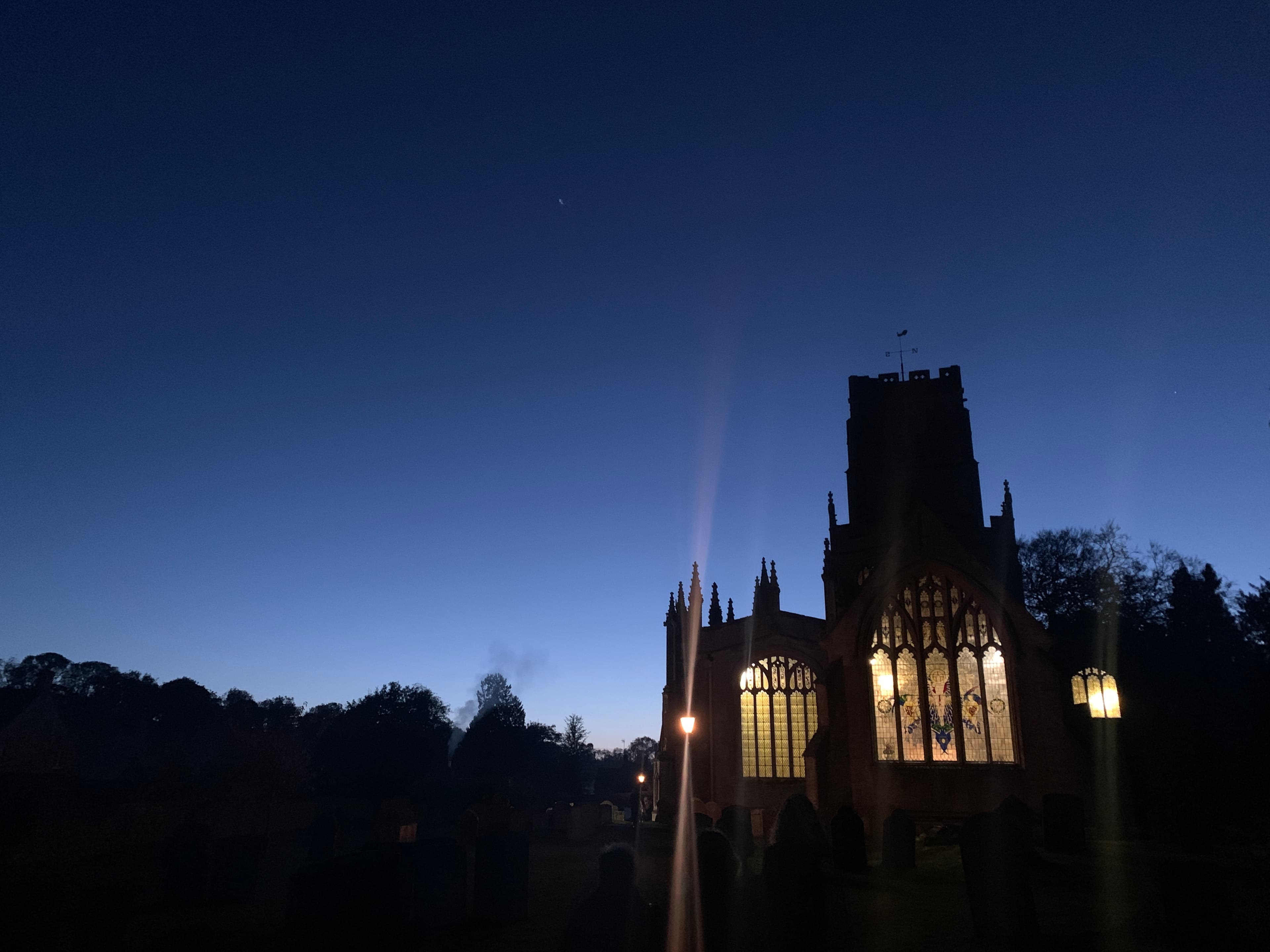St Peter and St Paul, Northleach — the 'Cathedral of the Cotswolds' — silhouetted against twilight sky with its windows glowing from inside