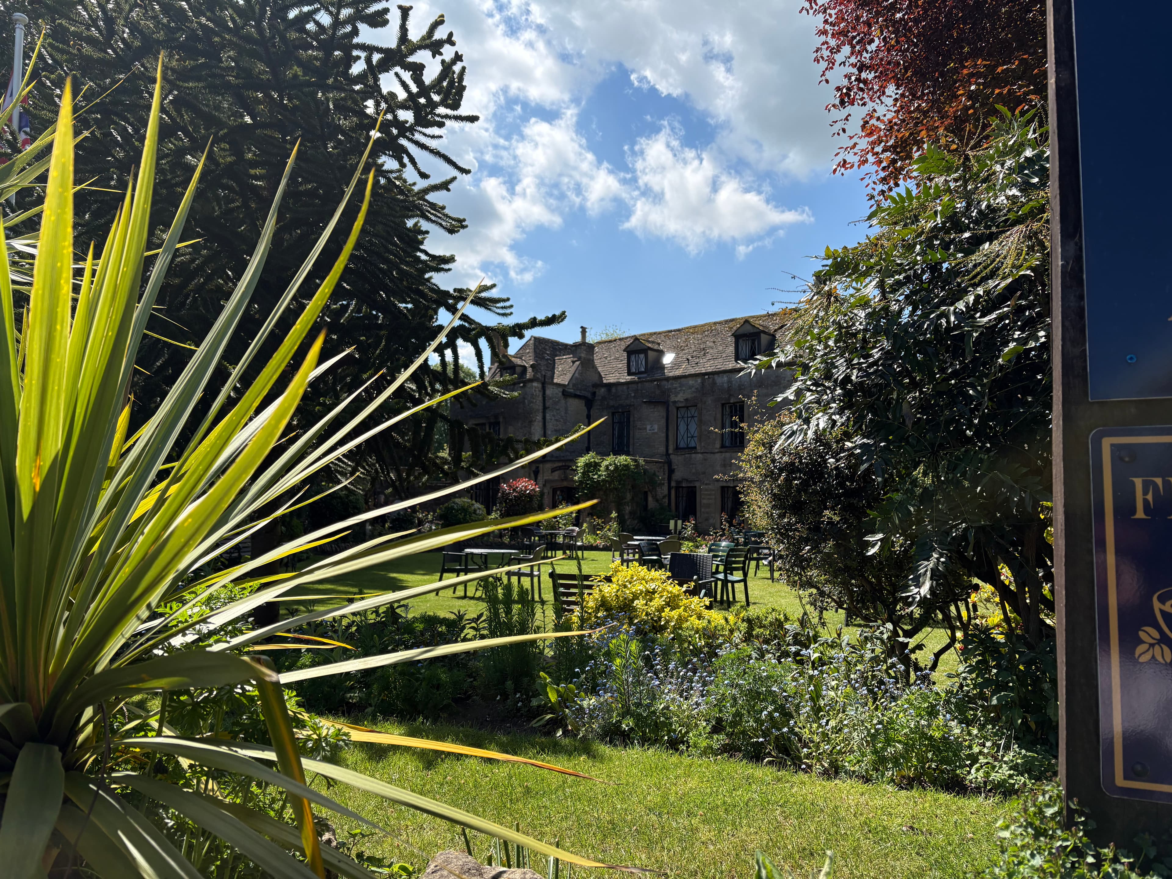 A walled hotel garden in Stow, with seating beneath the surrounding stone buildings